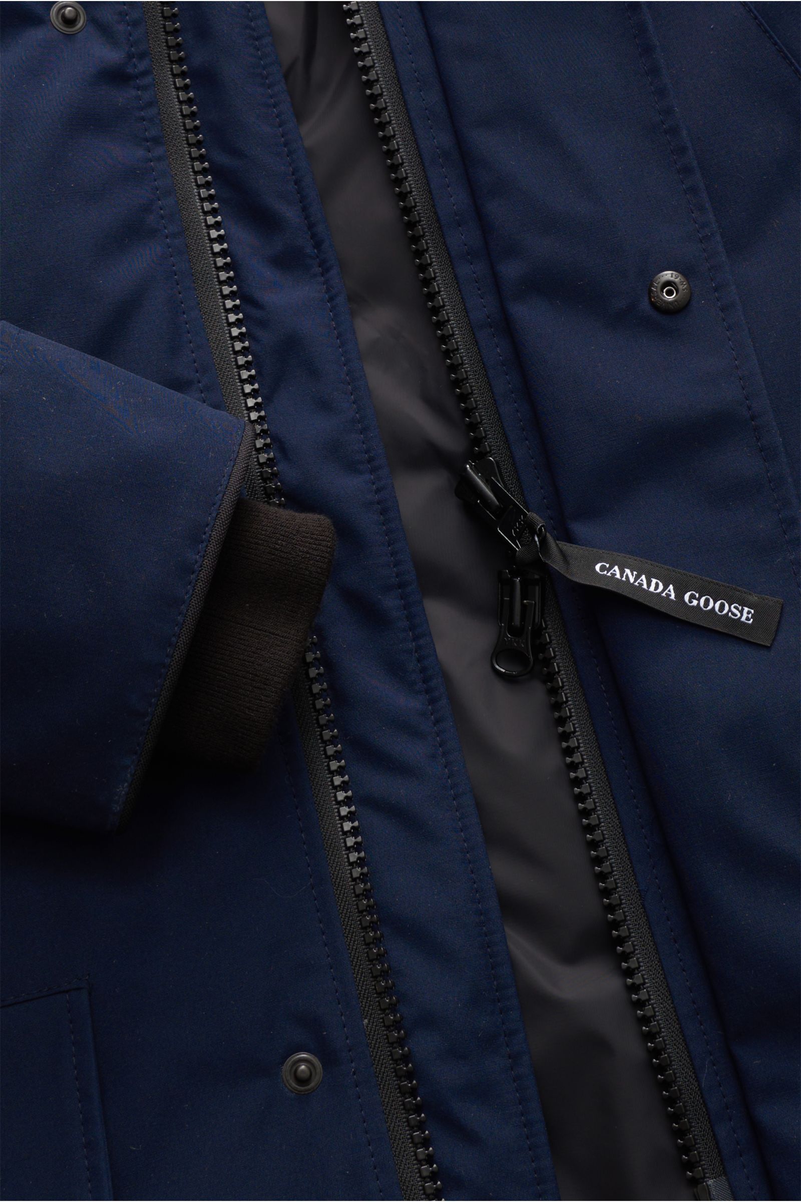 Nahaufnahme des Canada Goose Daunenparka 'Langford' navy von vorne mit geöffnetem Zwei-Wege-Reißverschluss, glattem Arctic-Tech-Material und Windblende.