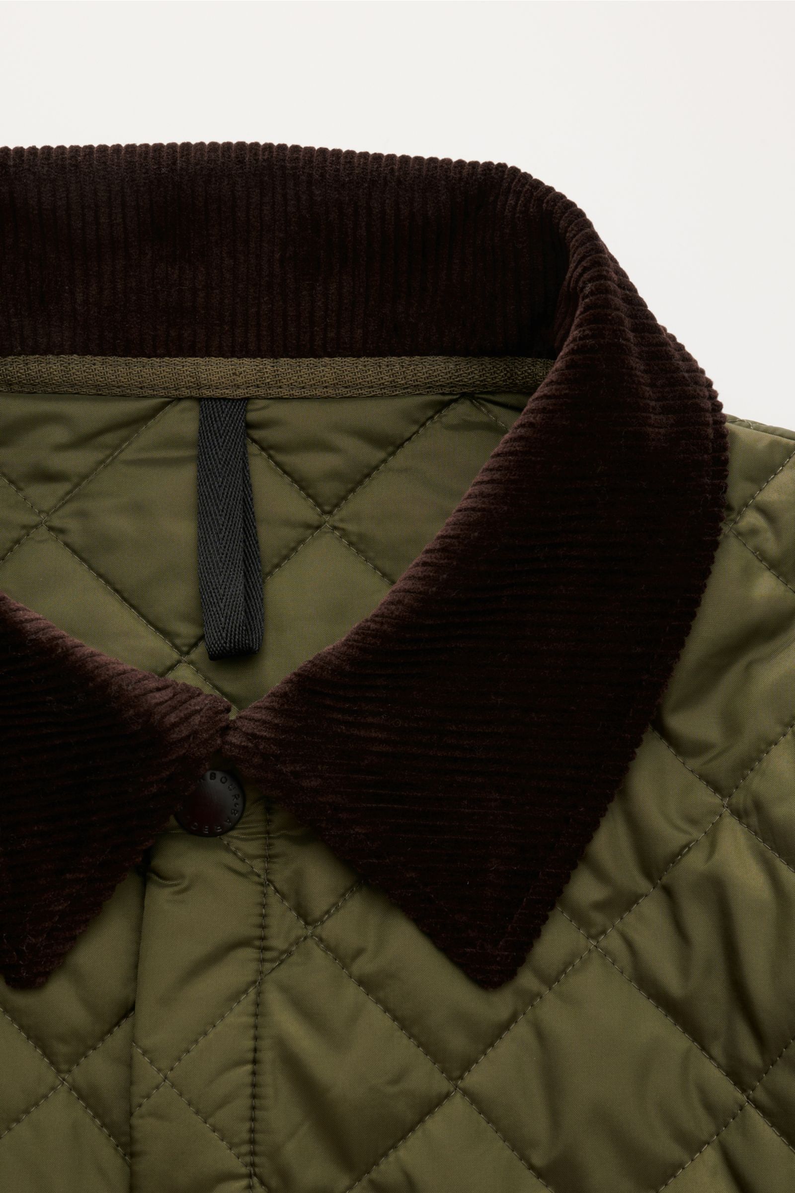Nahaufnahme der Barbour Steppjacke 'Liddesdale Quilt' oliv mit braunem Cord-Umlegekragen, leichter Wattierung und Druckknopfleiste.