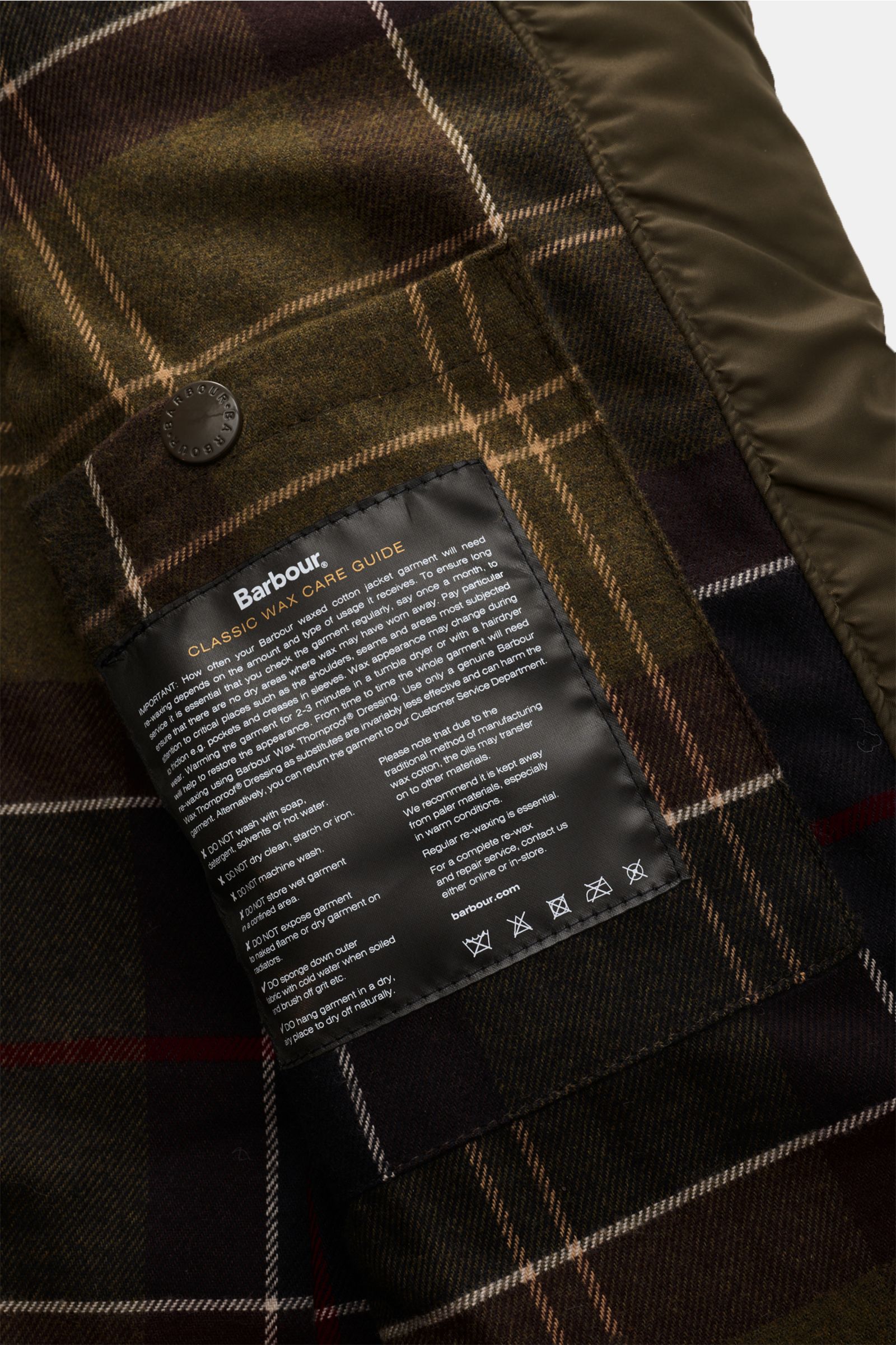 Close-up inside view of Barbour Waxed jacket 'Ogston' dark olive, showing classic tartan lining and care guide label.

Elegant, stylish, masculine: The modern waxed jacket 'Ogston' by BARBOUR in water repellent, waxed cotton with double front can not o