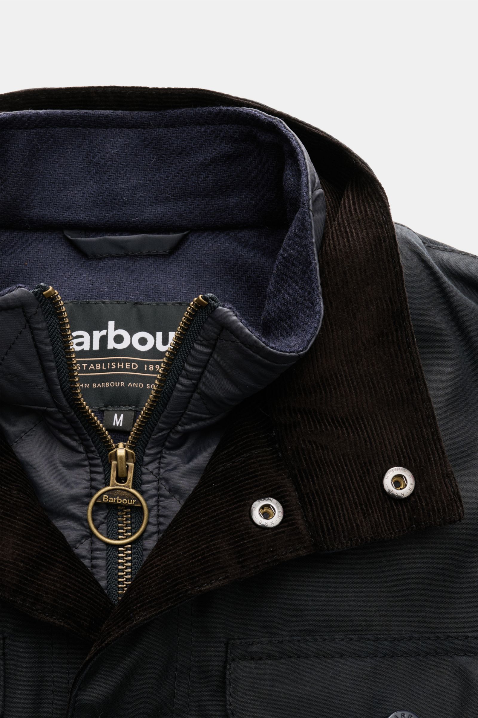Nahaufnahme der Barbour Wachsjacke 'Ogston' dark navy von oben, mit gewachster Baumwolle, Stehkragen aus Cord, wasserabweisend, Slim Fit, Druckknopf-Leiste.