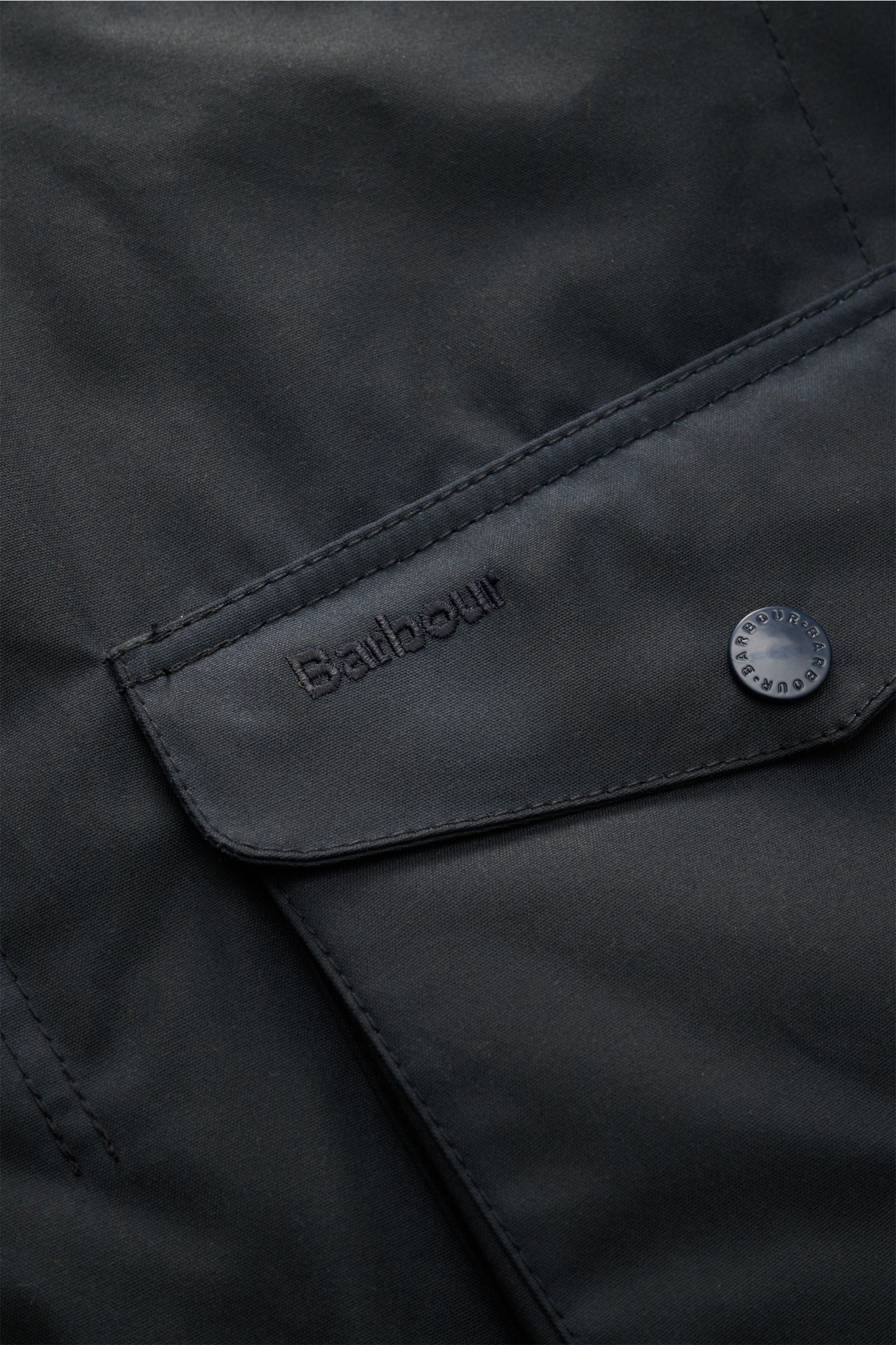 Nahaufnahme der Brusttasche der Barbour Wachsjacke 'Ogston' dark navy aus gewachster, wasserabweisender Baumwolle mit Druckknopf.