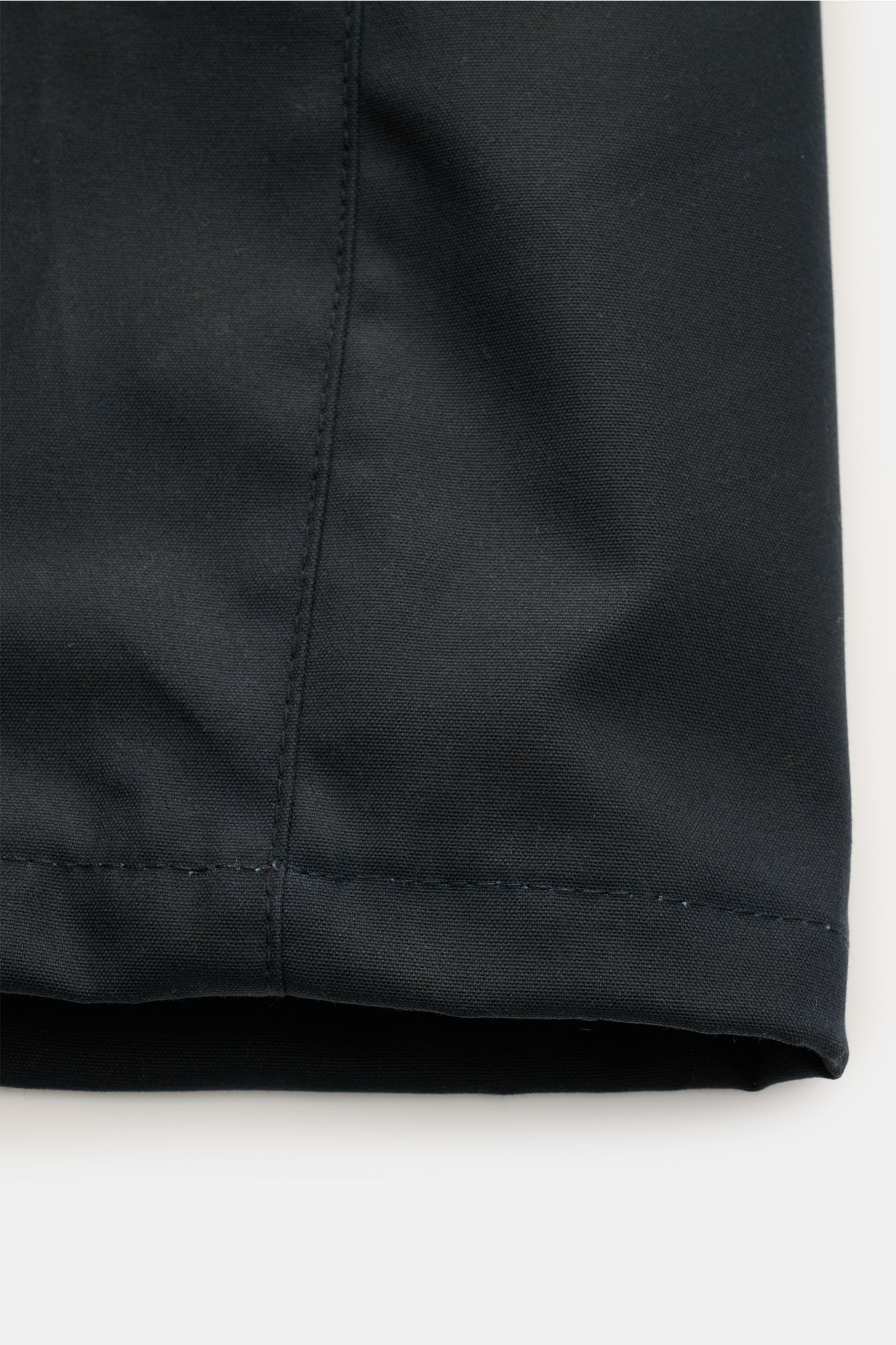 Nahaufnahme vom Saum der Barbour Wachsjacke 'Ogston' dark navy aus gewachster, wasserabweisender Baumwolle mit Slim Fit und charakteristischer Haptik.