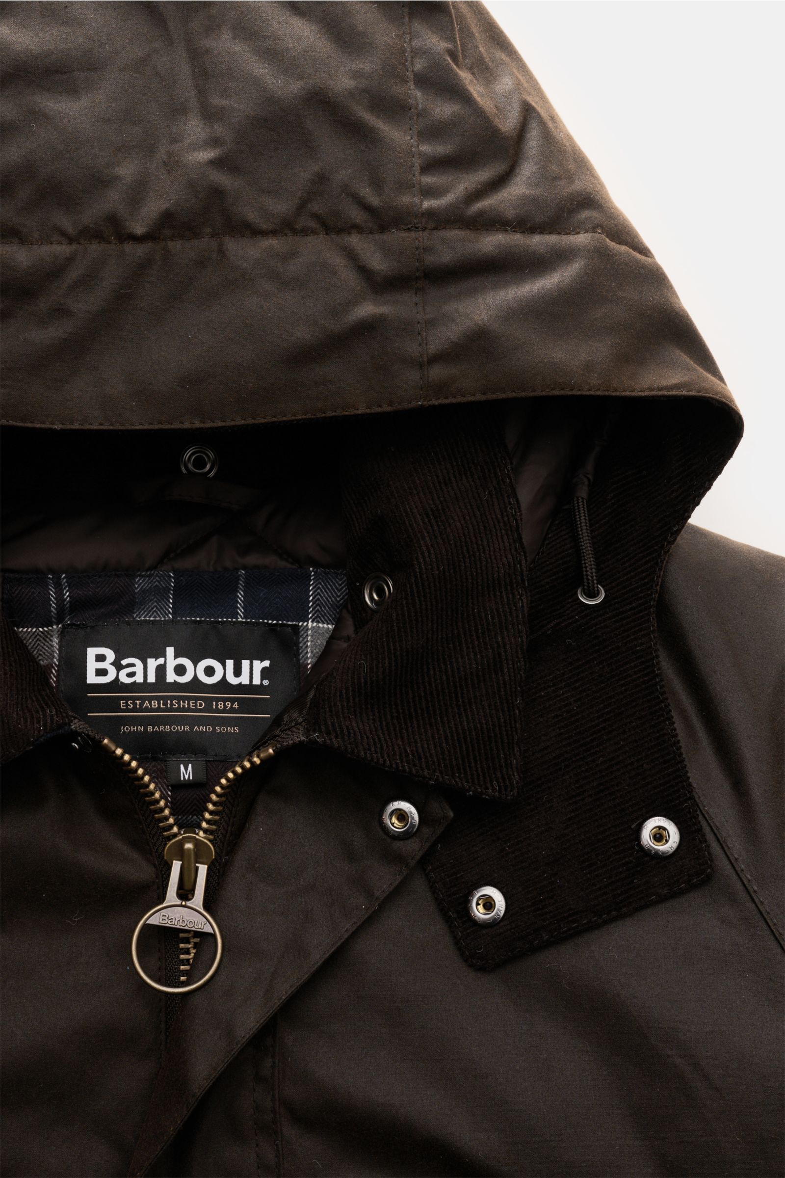 Nahaufnahme der Barbour Wachsjacke 'Modern Beaufort' dark olive mit gewachster Baumwolle, abnehmbarer Kapuze, Umlegekragen und Reißverschluss.