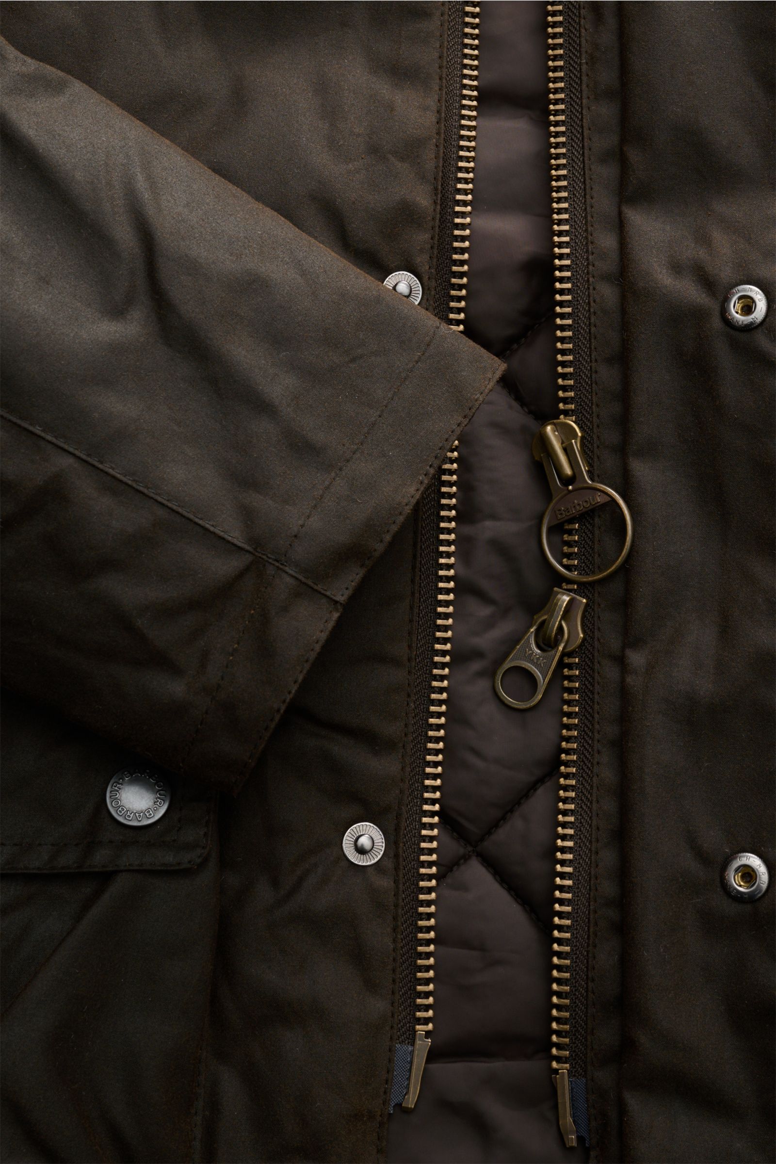 Nahaufnahme der Barbour Wachsjacke 'Modern Beaufort' dark olive von vorne, mit geöffnetem Zwei-Wege-Reißverschluss, gewachster Baumwolle und Wattierung.