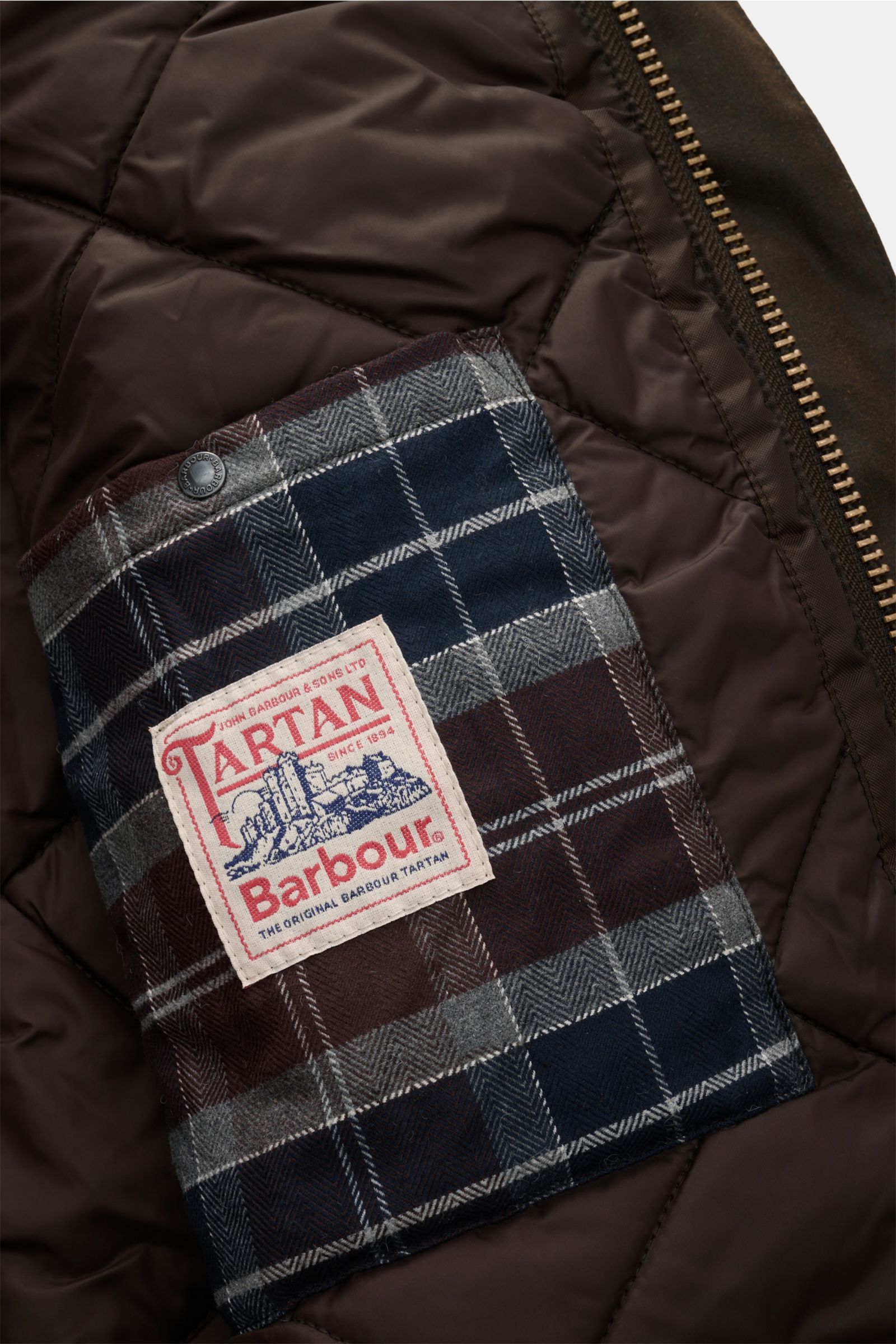 Innenansicht der Barbour Wachsjacke 'Modern Beaufort' dark olive mit wattierter Innenseite, Tartan-Innentasche und Reißverschluss.