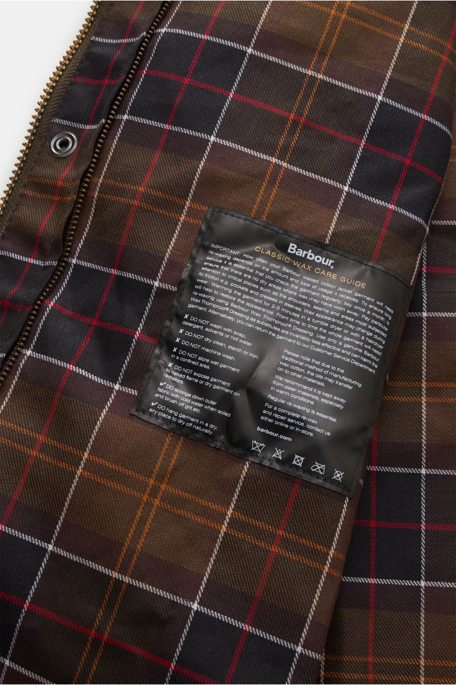 Close-up interior view of Barbour Waxed jacket 'Beaufort' dark olive showing classic tartan lining and care guide label. A true classic from BARBOUR: The long waxed jacket 'Beaufort' made of water repellent, waxed cotton with corduroy collar has occupied 
