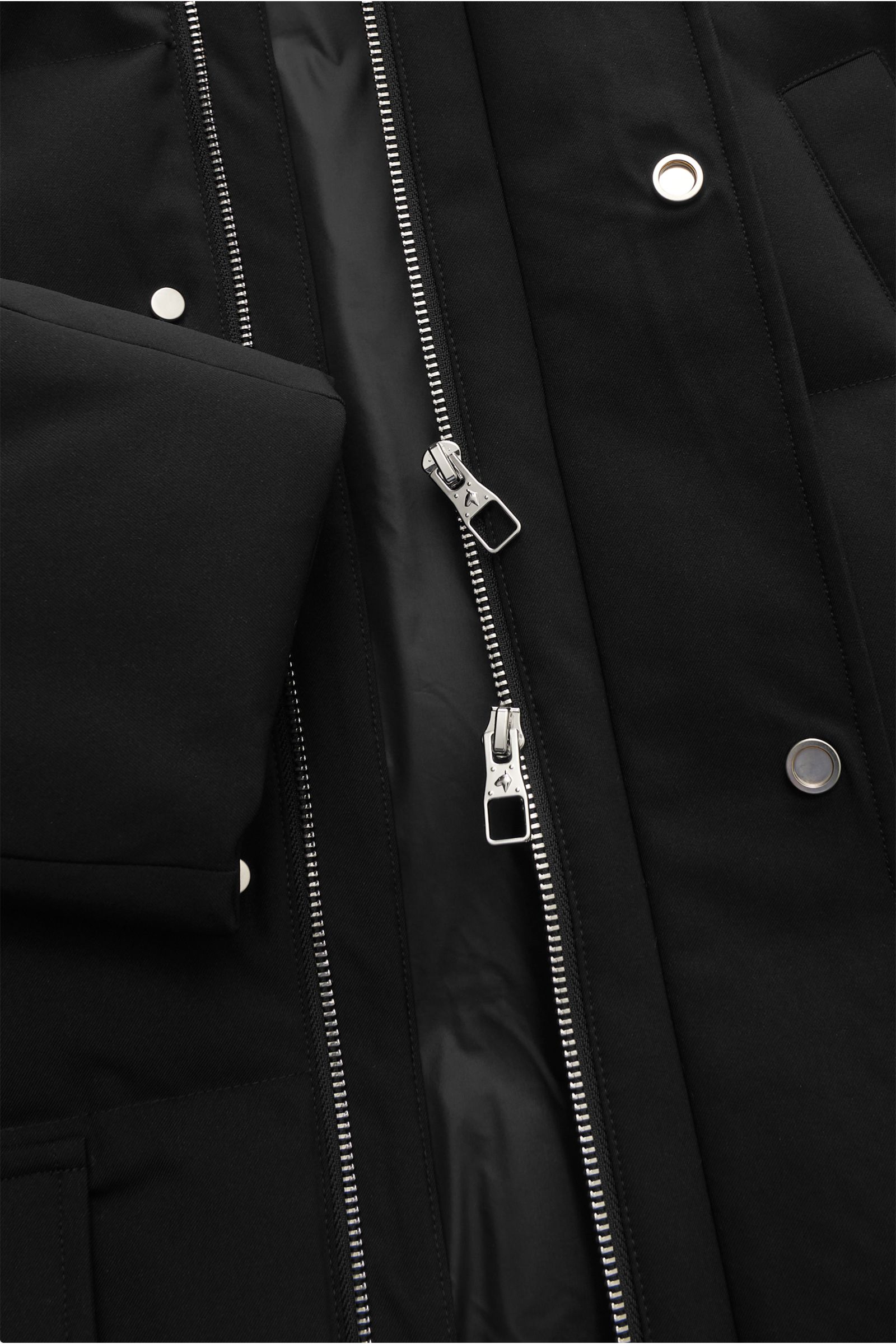 Nahaufnahme der geöffneten Montecore Daunenjacke schwarz von oben, zeigt Twill-Microfaser, weichen Griff, wärmende Daunenfüllung, gesteppte Optik, Regular Fit, Zwei-Wege-Reißverschluss, Windblende mit Druckknöpfen, Kapuze, schräge Fronttaschen, Hüfttasche