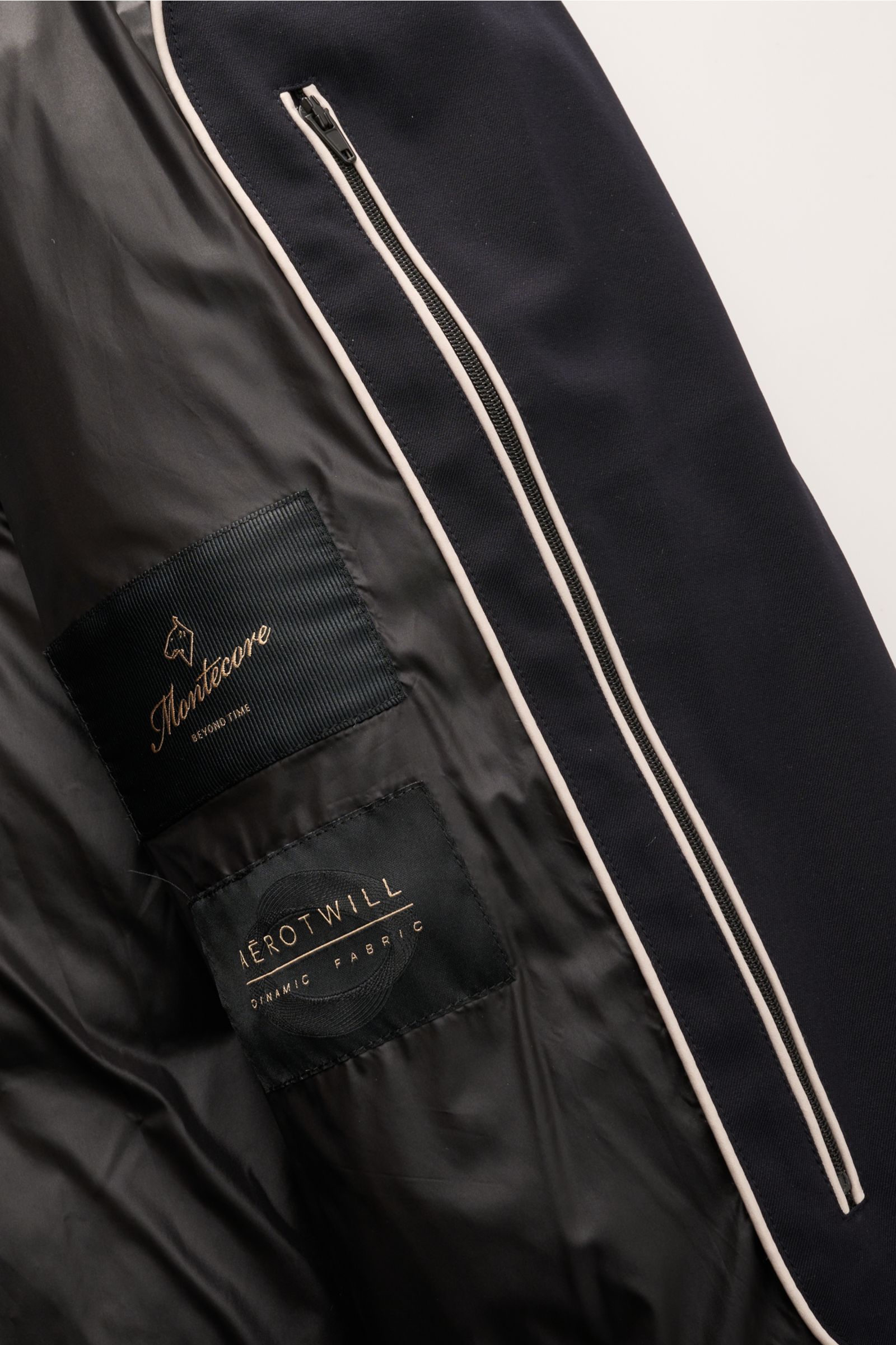 Close-up interior view of the Montecore Down coat dark navy showing black lining, two fabric labels, and a zip pocket, highlighting high-quality microfibre, slightly robust touch, wind and water repellent, breathable, duck down lining, regular fit, robust