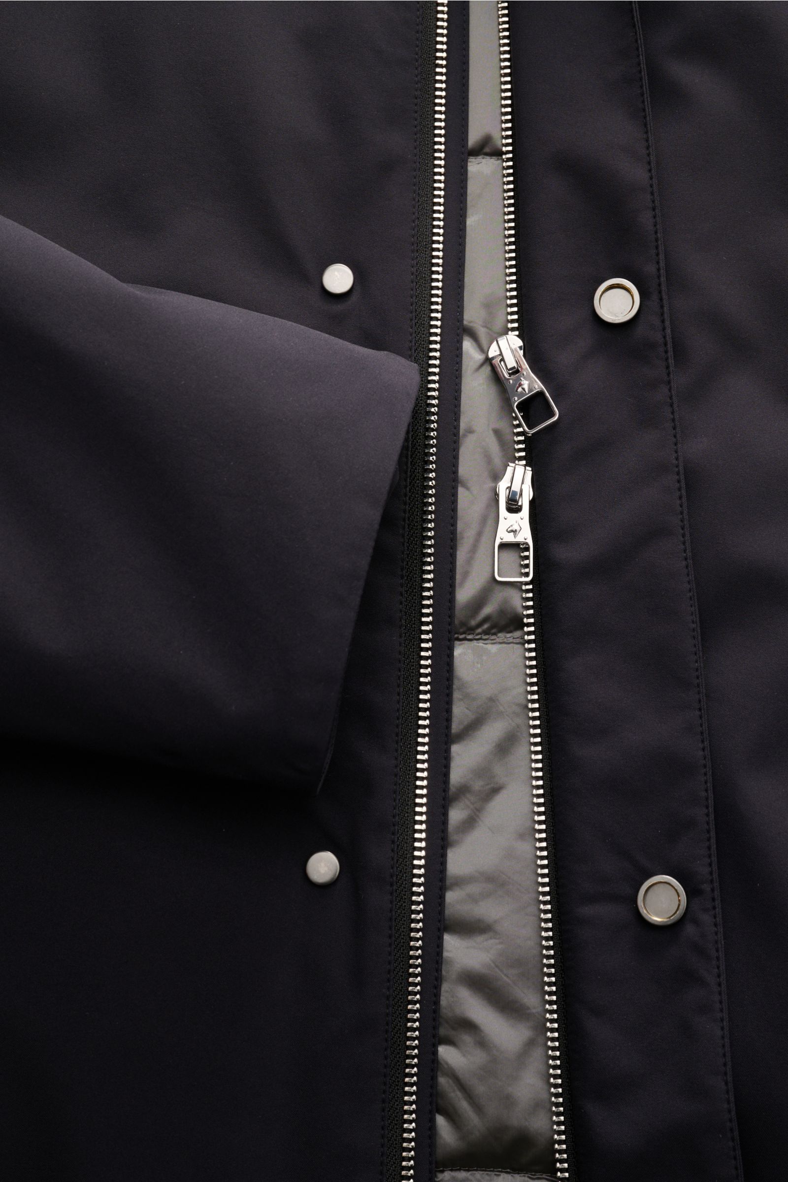 Close-up front view of the Montecore Daunenjacke navy showing the silver two-way zipper, snap buttons, smooth microfiber fabric, and part of the sleeve. Zeitloses Essential für kältere Tage: Die komfortable Daunenjacke von MONTECORE bietet zahlreiche Komb