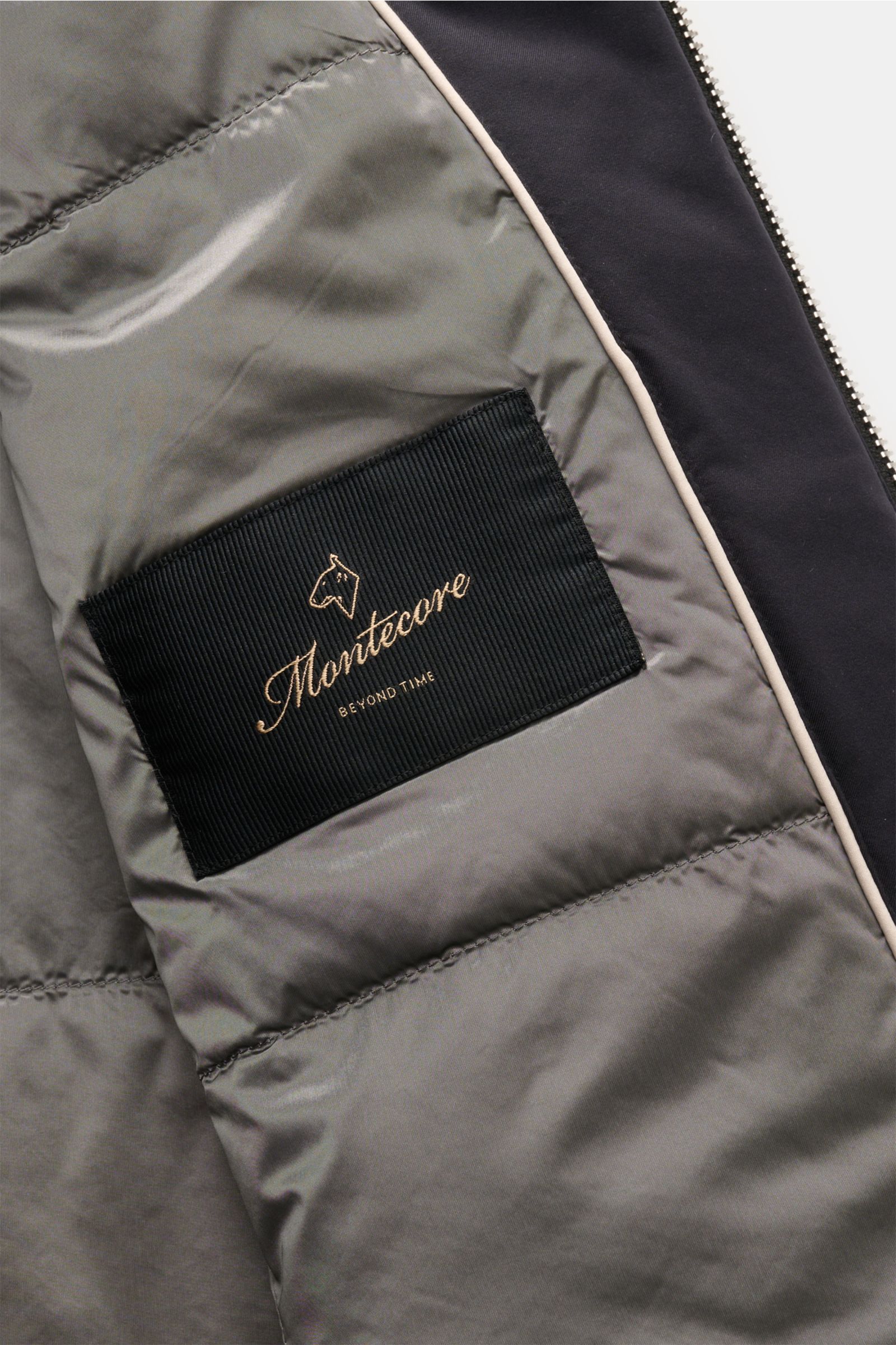 Close-up inside view of the Montecore Daunenjacke navy showing smooth microfiber lining, black label with logo, and part of the two-way zipper.