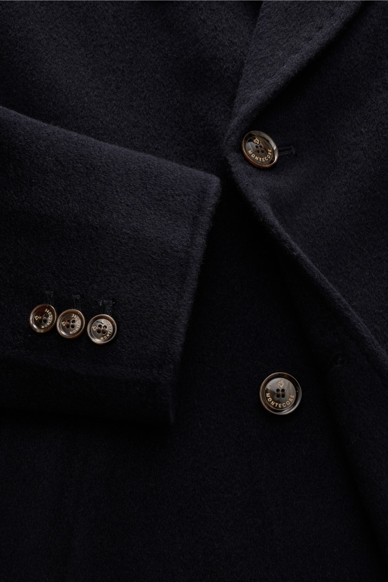 Close-up front-side view of Montecore Cashmere Cabanjacke navy, showing soft pure cashmere fabric, slim fit, double-breasted three-button style, peak lapels, angled welt pockets, buttoned sleeve cuffs, unlined interior, and an inner pocket. 

Klassisch