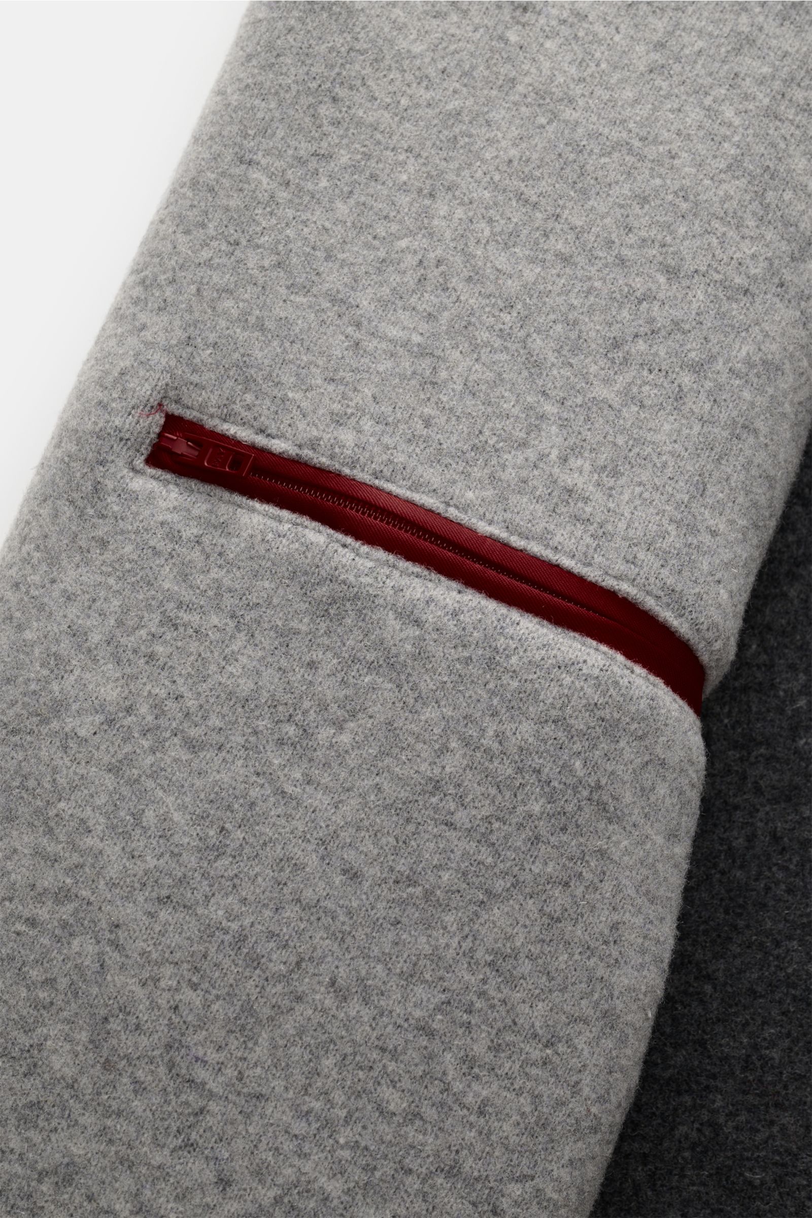 Nahaufnahme des Ärmels der Fay Jacke 'Duty Jacket' grau meliert aus weichem Jersey-Woll-Microfaser-Mix mit rotem Reißverschluss innen.