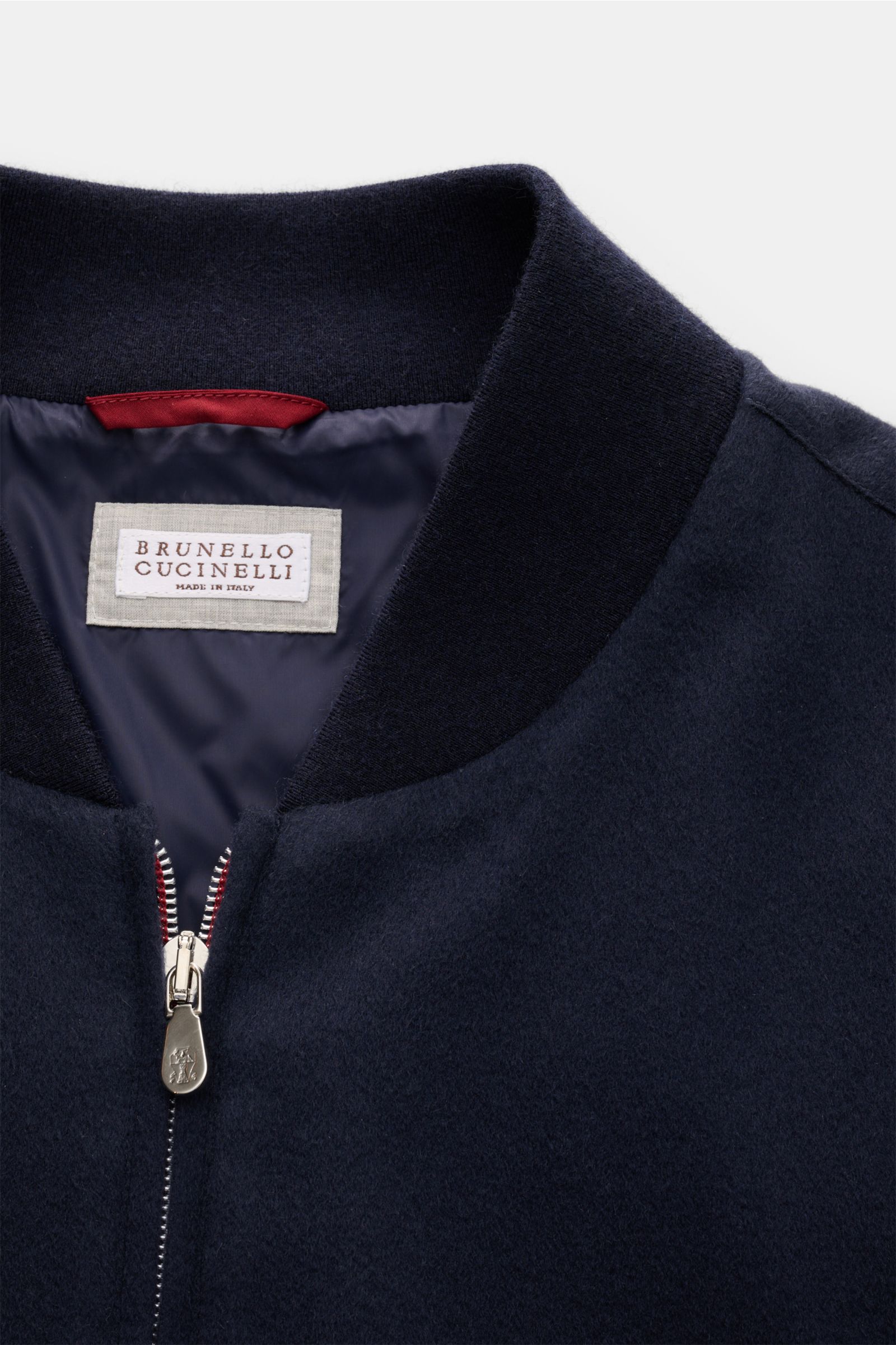 Nahaufnahme des Brunello Cucinelli Cashmere Blouson navy von oben, zeigt weichen Rippstrickkragen, Zwei-Wege-Reißverschluss und halb gefüttertes Innenfutter.