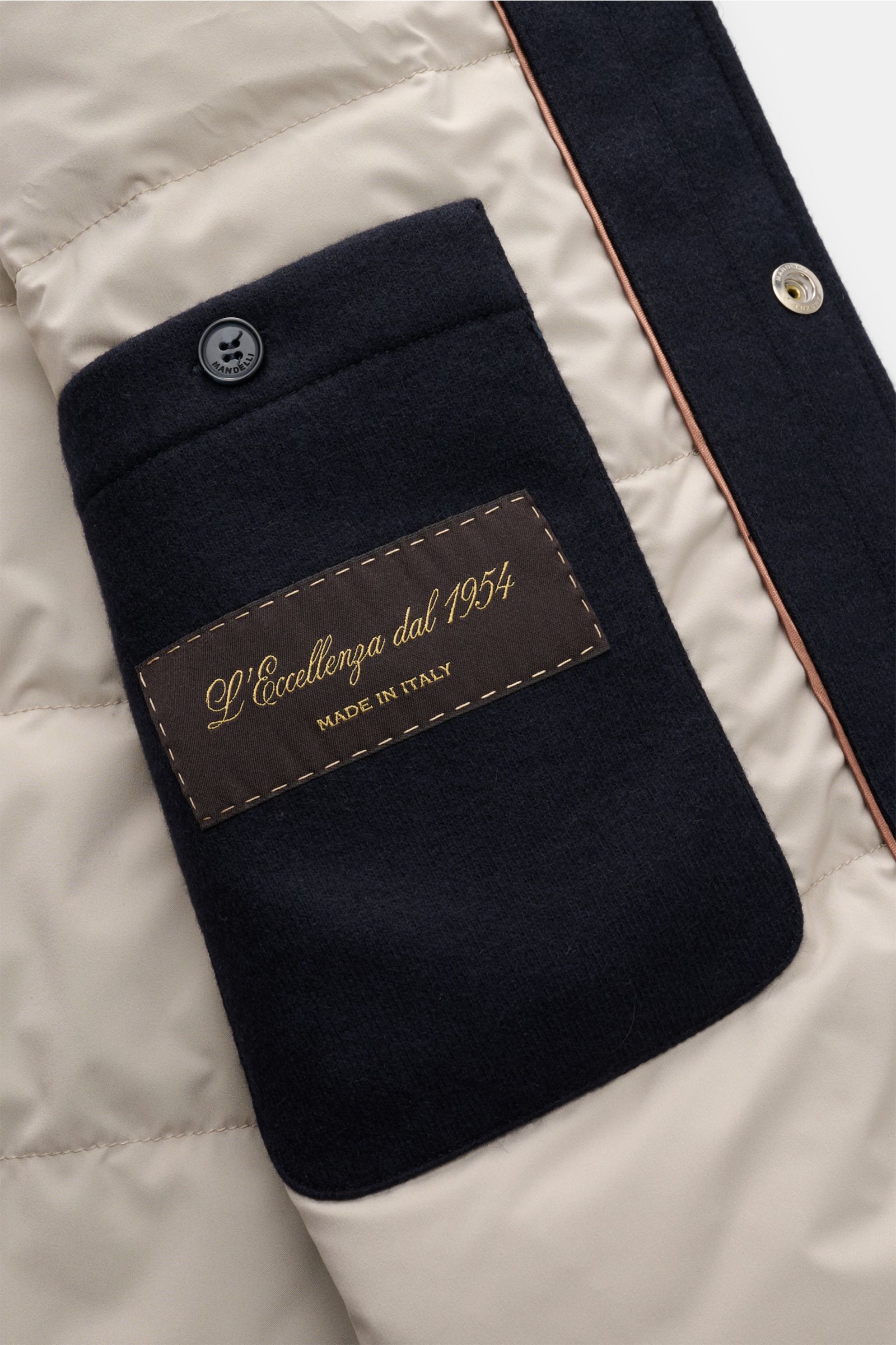 Close-up inside view of the Mandelli Cashmere Daunenjacke navy showing the soft inner pocket with button and label, quilted lining, and snap closure.

Luxuriöse Herbstlooks: Die edle MANDELLI Cashmere Jacke im Overshirt-Design bietet mit ihrer Daunenfü