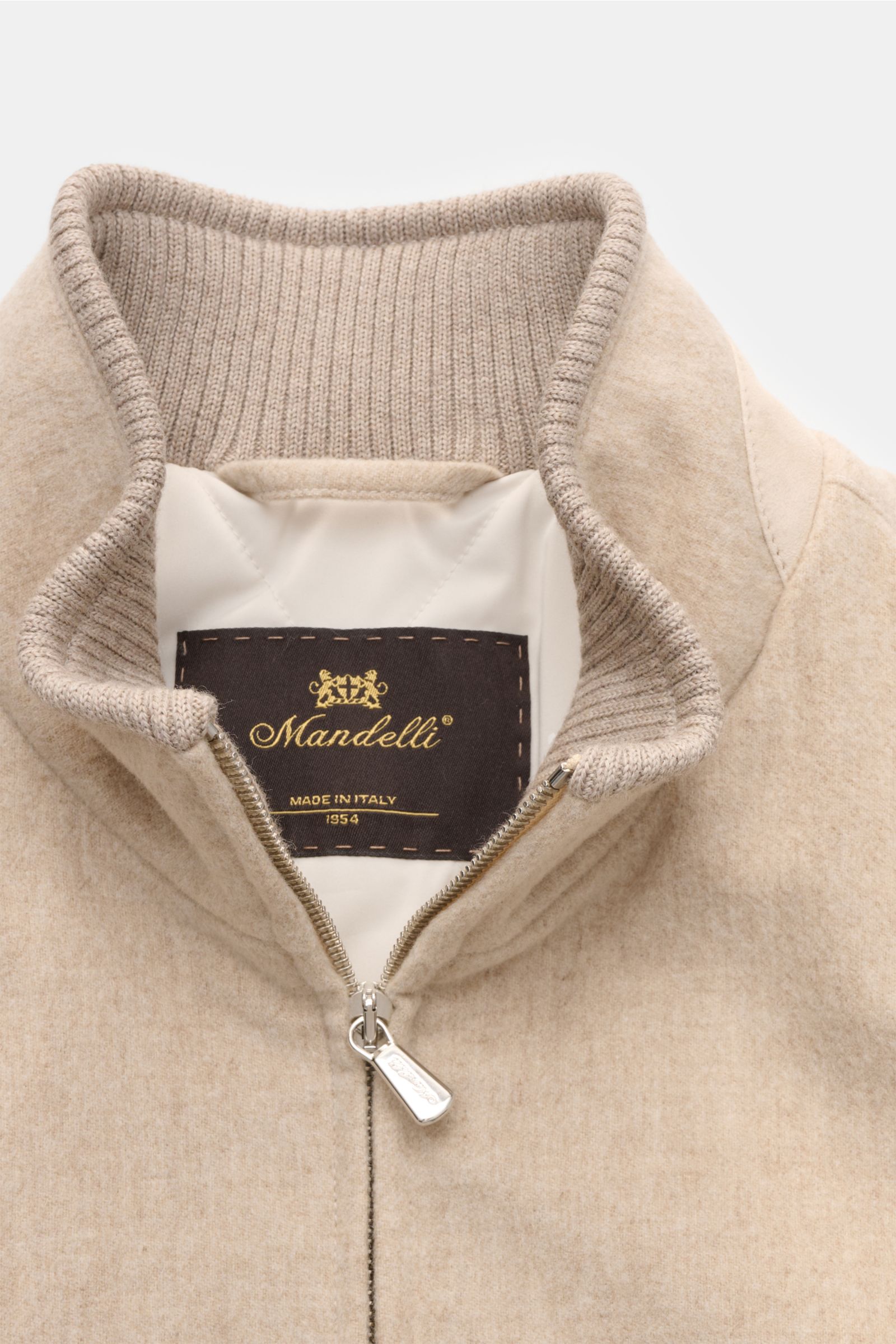 Close-up front view of the Mandelli Cashmere Blouson beige showing the zipper, ribbed collar, and inner label, made of reiner Cashmere, very soft touch, Slim Fit.  
-

reiner Cashmere
sehr weicher Griff
Slim Fit
 