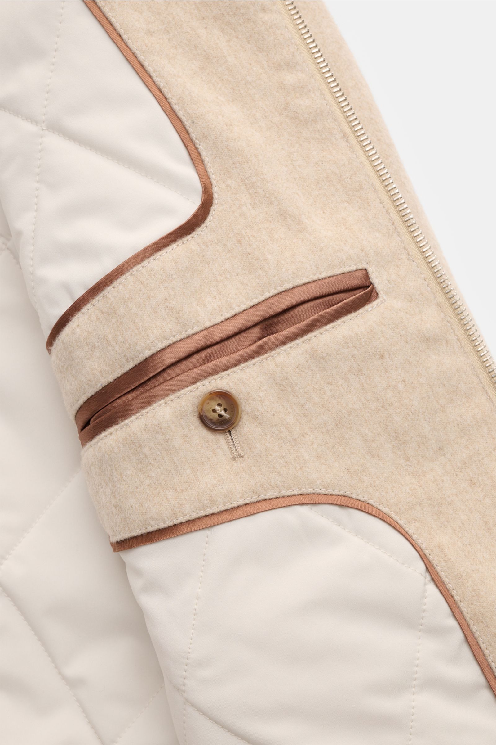 Close-up inside view of Mandelli Cashmere Blouson beige showing beige reiner Cashmere fabric with brown trim, button detail, and quilted lining, photographed from an angled perspective. -

reiner Cashmere
sehr weicher Griff
