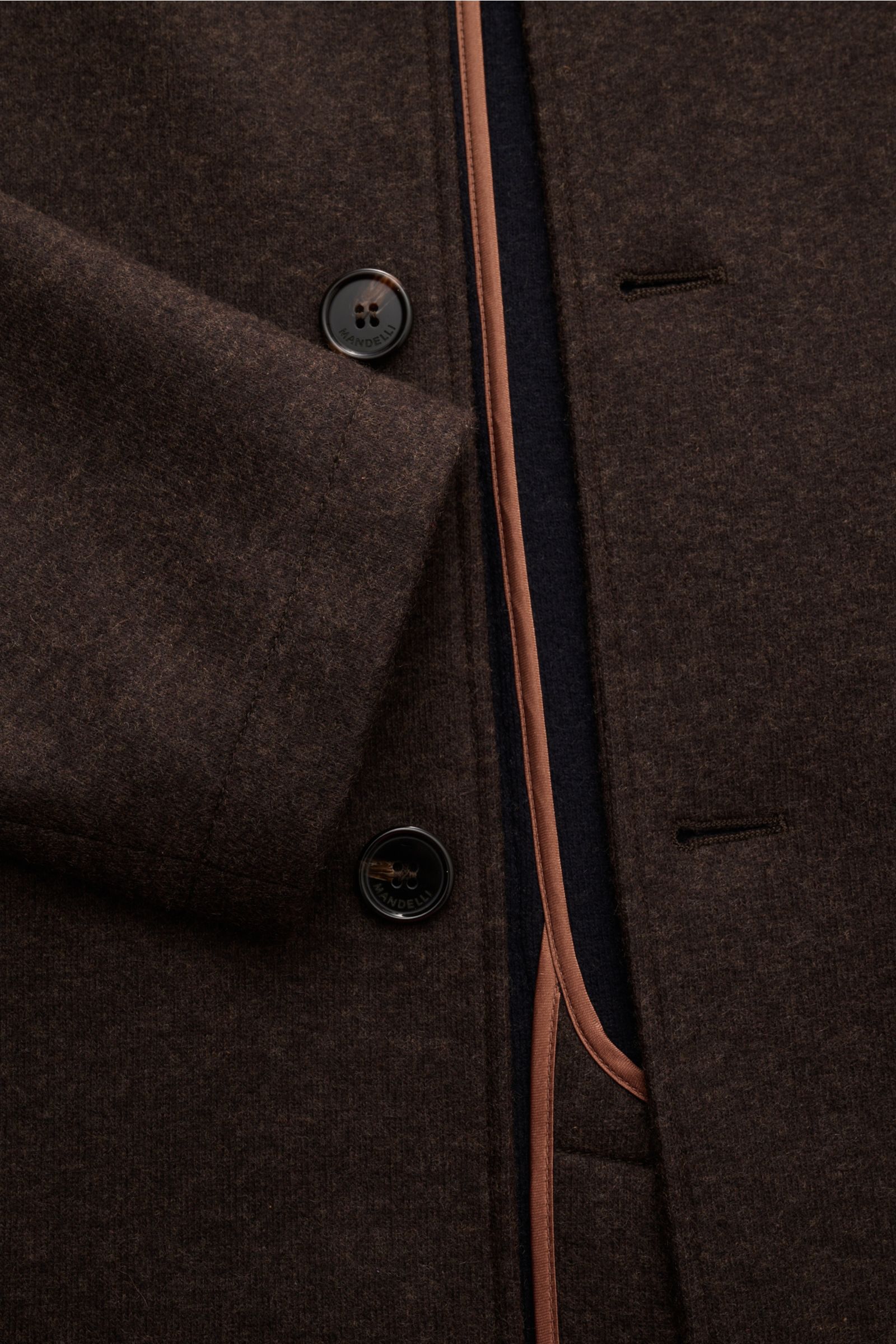 Nahaufnahme der Mandelli Cashmere Jacke dunkelbraun meliert von schräg oben, zeigt Knopfleiste, Manschette, Stehkragen mit Nerz-Besatz, Jersey, Slim Fit, weiche Haptik, schräge Taschen, Rippbündchen, ungefüttert, zwei Innentaschen, reiner Cashmere.