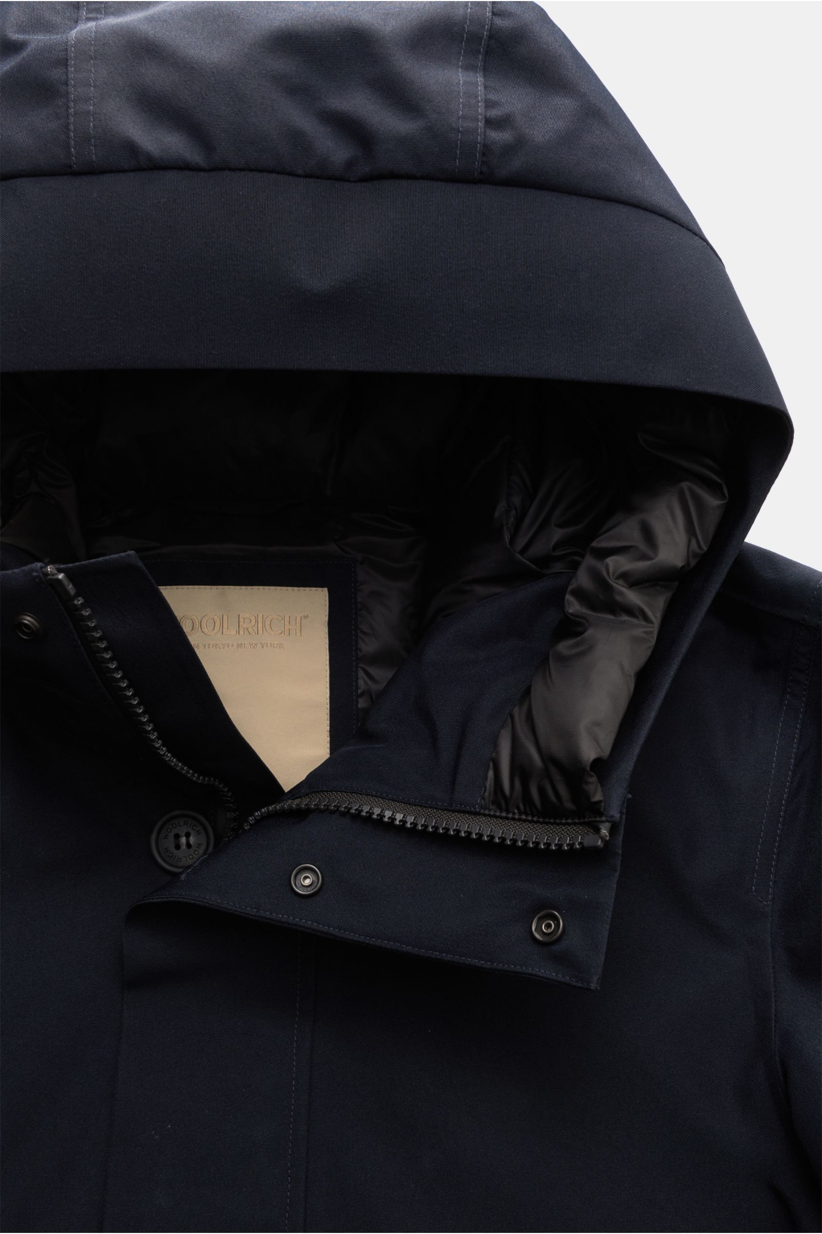 Close-up front view of the Woolrich Daunenjacke dark navy showing the high collar with hood, robust two-way zipper, buttoned wind flap, and part of the functional GORE-TEX microfiber fabric. Features include wind- and waterproof, breathable, warm down fil