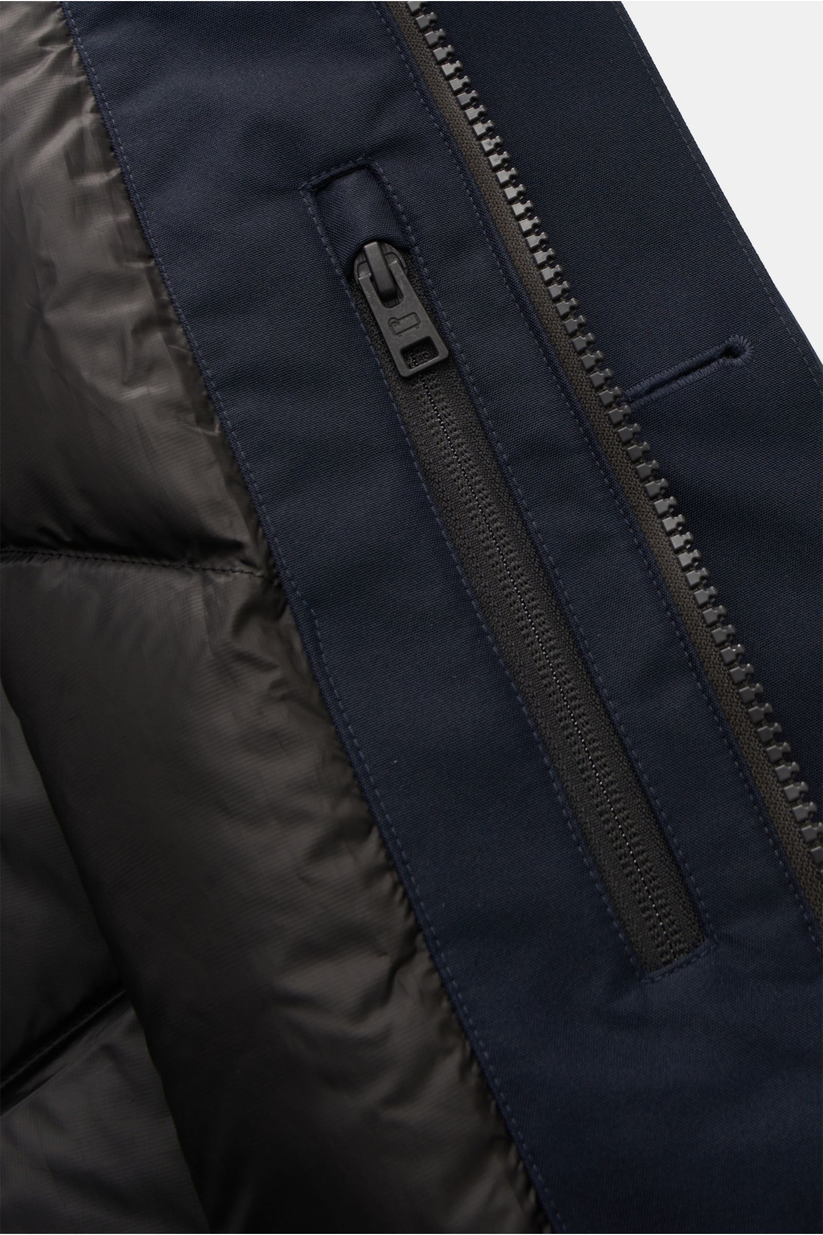 Close-up view of the zipper area and inner lining of the Woolrich Daunenjacke dark navy, featuring funktionale Microfaser (GORE-TEX), wind- und wasserdicht, atmungsaktiv, wärmende Daunenfüllung, getapte Nähte, Slim Fit, robuster Zwei-Wege-Reißverschluss, 