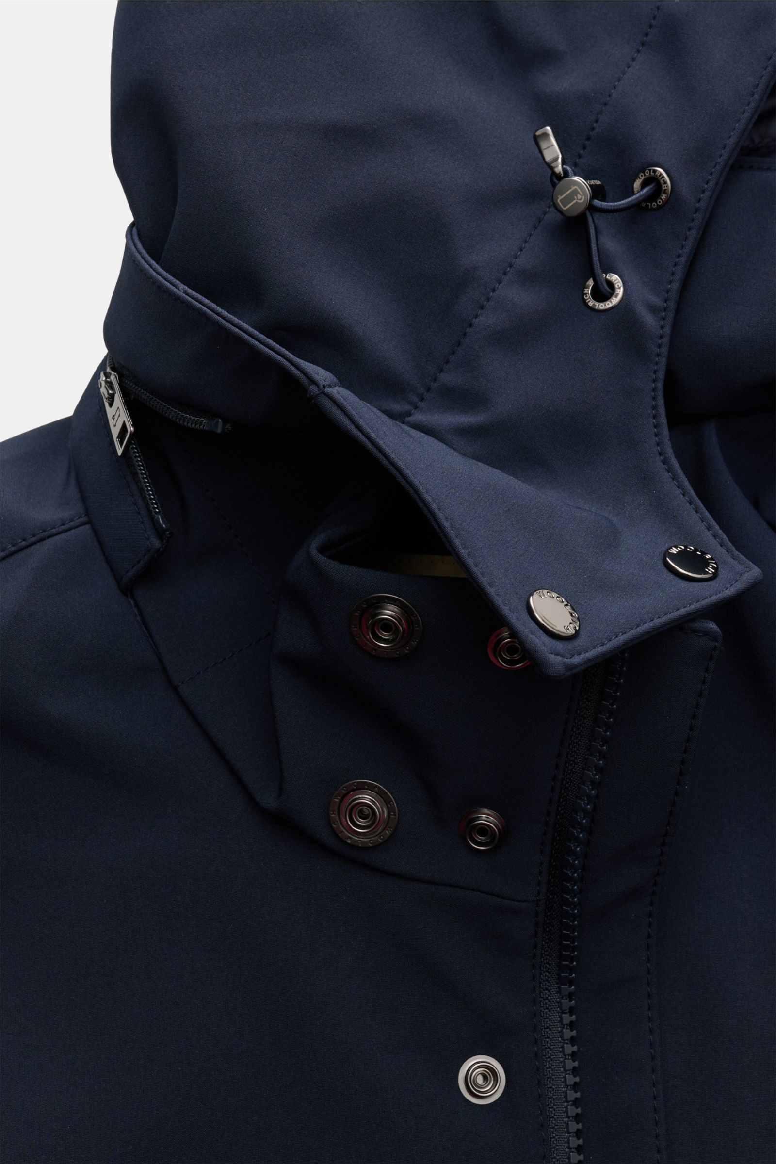 Close-up front view of the Woolrich Softshell-Daunenparka schwarz, showing its elastic microfiber softshell, smooth water-repellent surface, robust two-way zipper, snap buttons, and adjustable hood with drawstrings. Der moderne Softshell-Parka des Trad