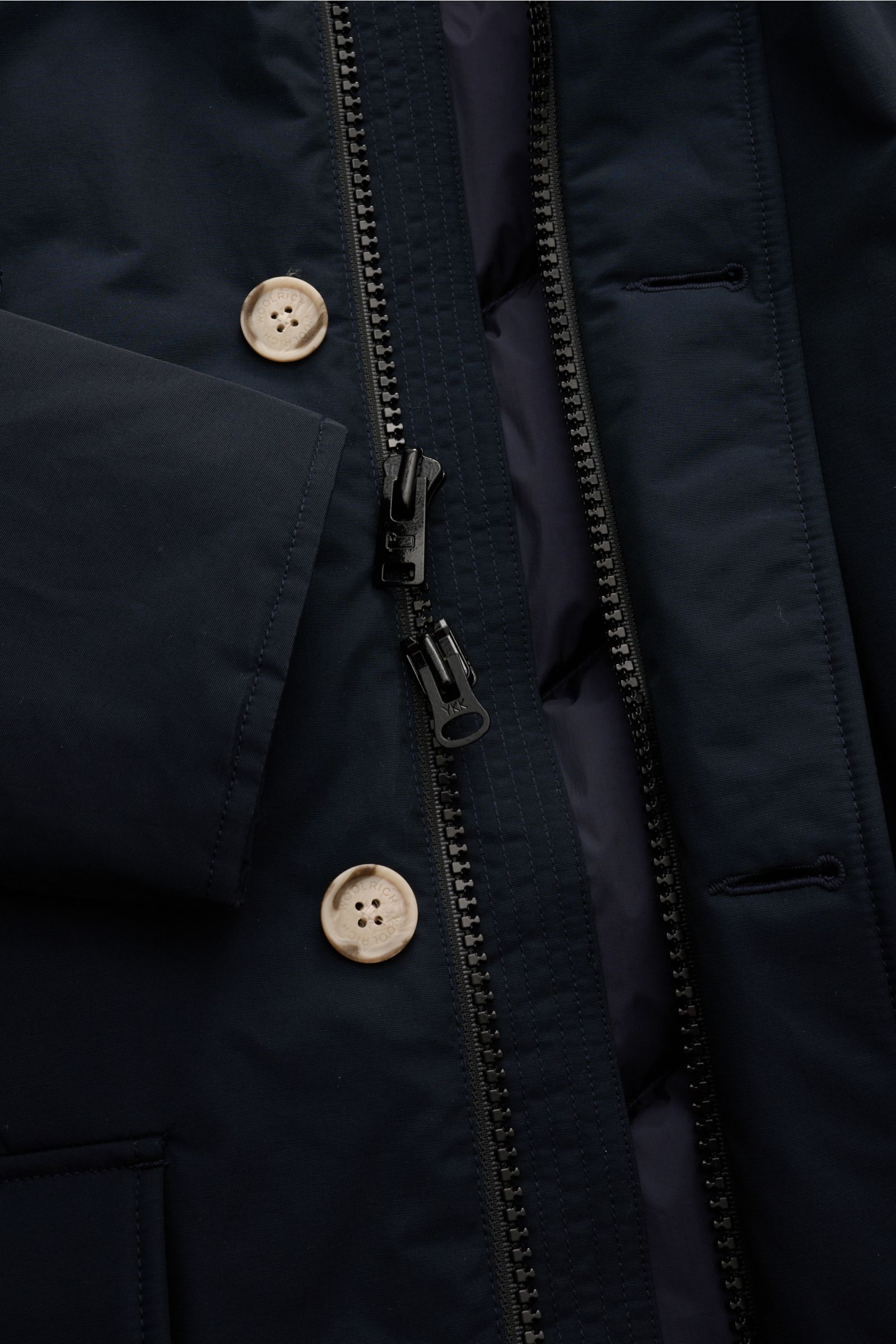 Close-up front view of the Woolrich Daunenparka 'Arctic Parka' navy, showing the dual zipper, buttons, and fabric texture. Kälte? Kann kommen. Der 'Arctic Parka' von WOOLRICH liefert sportiven Style und verlässliche Wärme bis –20 °C – dank hochwertiger, R