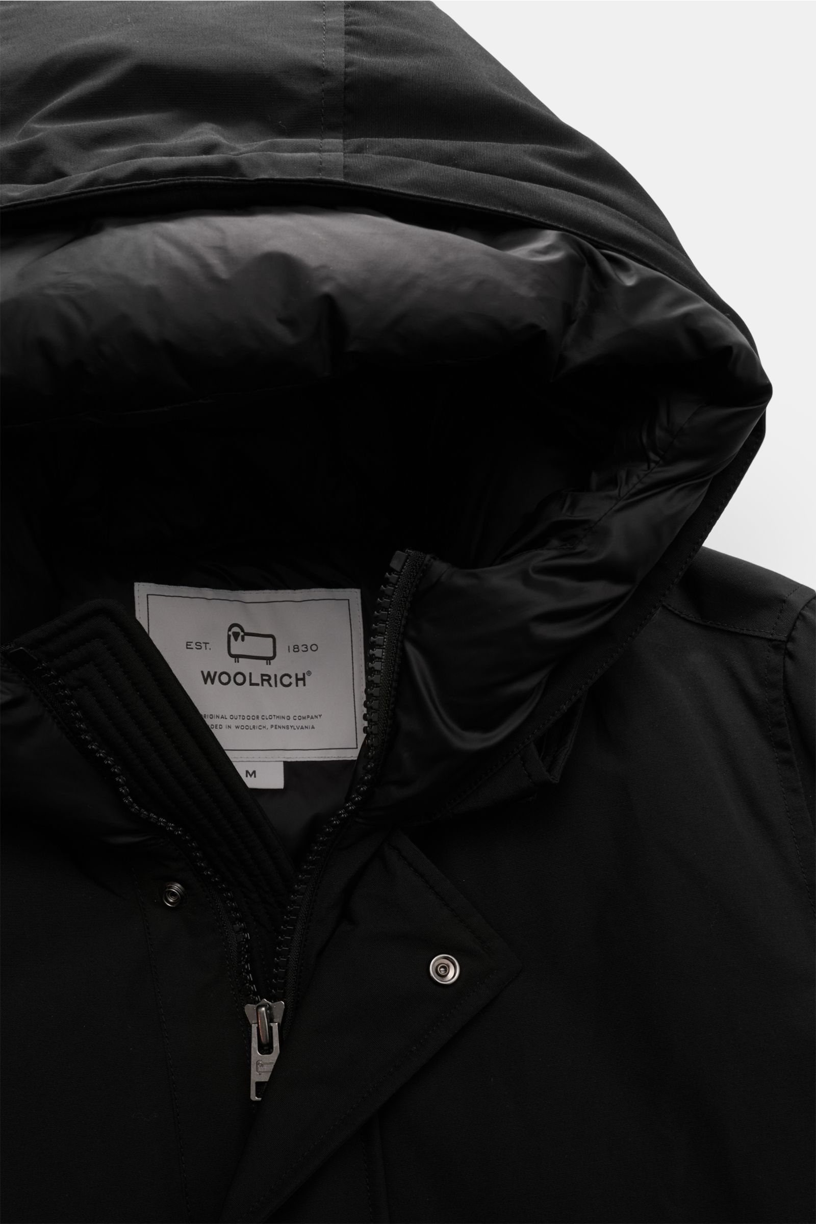 Nahaufnahme des schwarzen Woolrich Daunenparka 'Polar High Collar' von oben, mit wattierter Kapuze, robustem Zwei-Wege-Reißverschluss und winddichtem Ramar Cloth-Gewebe.