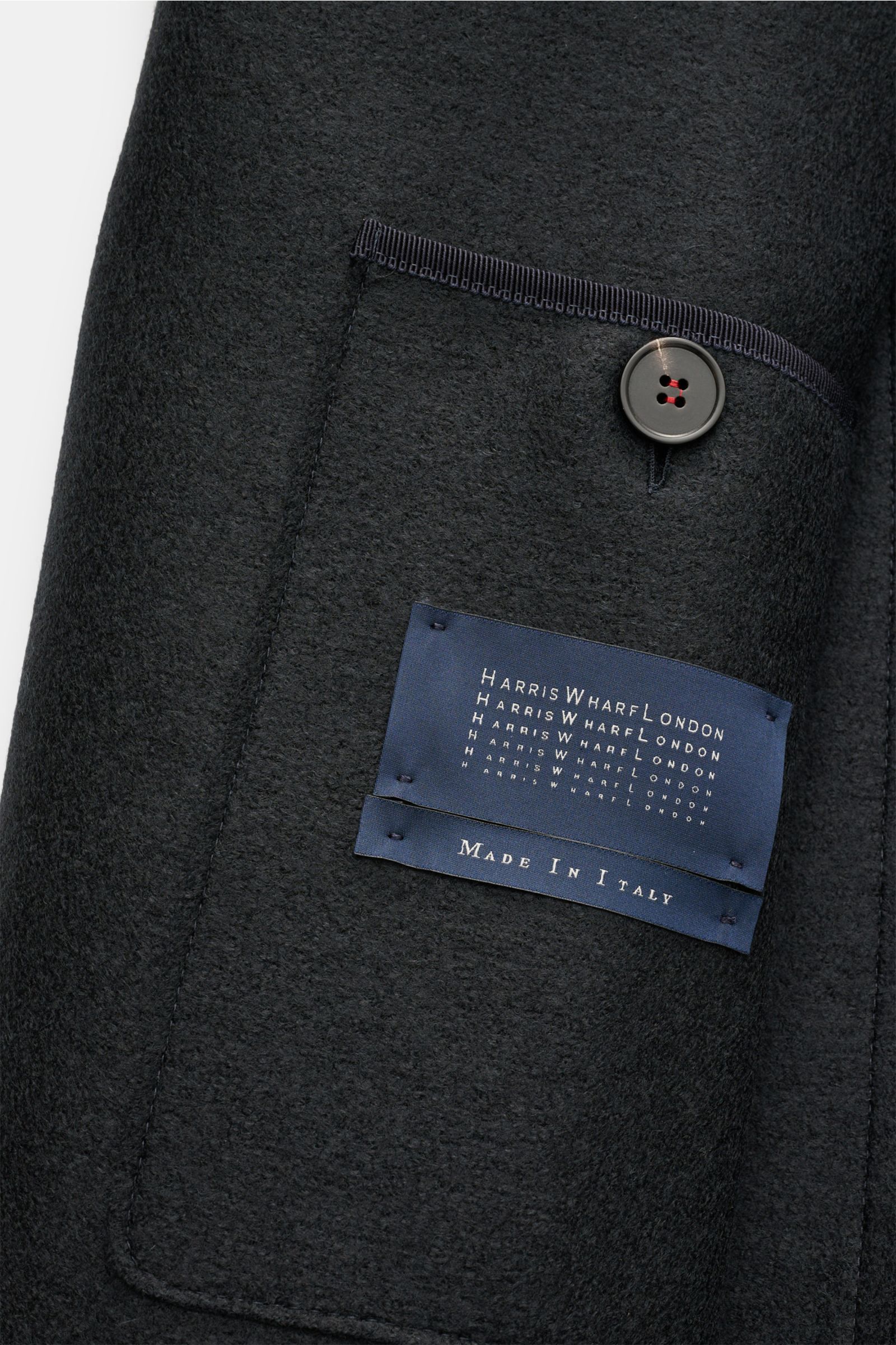 Nahaufnahme einer geknöpften Brusttasche der Harris Wharf London Wolljacke navy aus reiner, gefilzter Schurwolle, ungefüttert, mit Label „Made in Italy“.