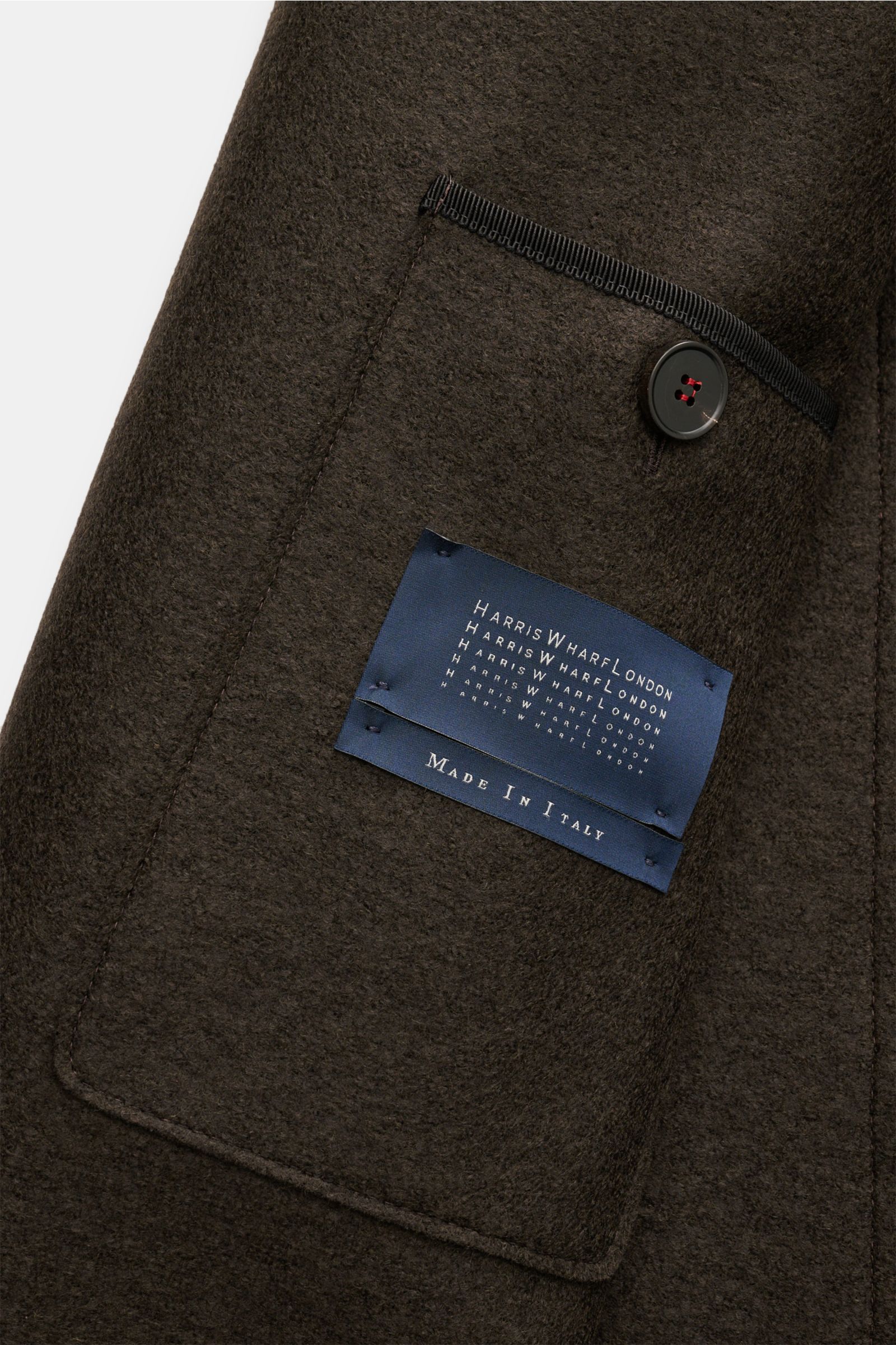 Harris Wharf London Wolljacke dunkelbraun aus gefilzter Schurwolle, Detailansicht der Brusttasche mit Knopf und Label in Nahaufnahme.