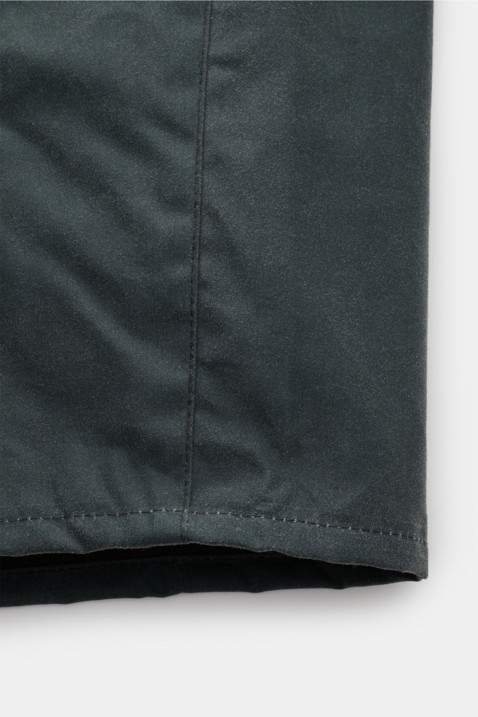 Barbour Wachsjacke 'Transport' petrol aus gewachster Baumwolle, Nahaufnahme des unteren Saums, robust und oversized, typisches Tartan-Innenfutter.