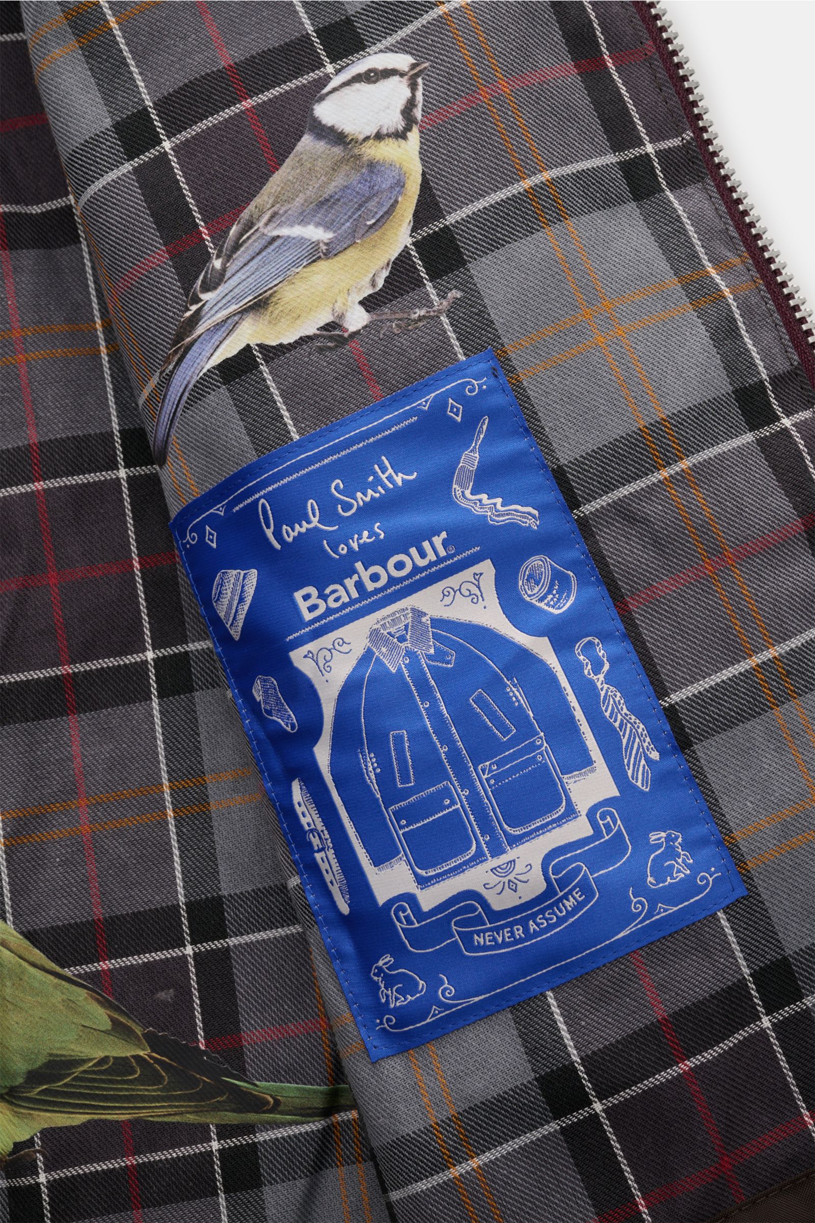Detailaufnahme des Tartan-Innenfutters mit Vogel-Prints und Paul Smith loves Barbour Label der Barbour Wachsjacke 'Transport' bordeaux.