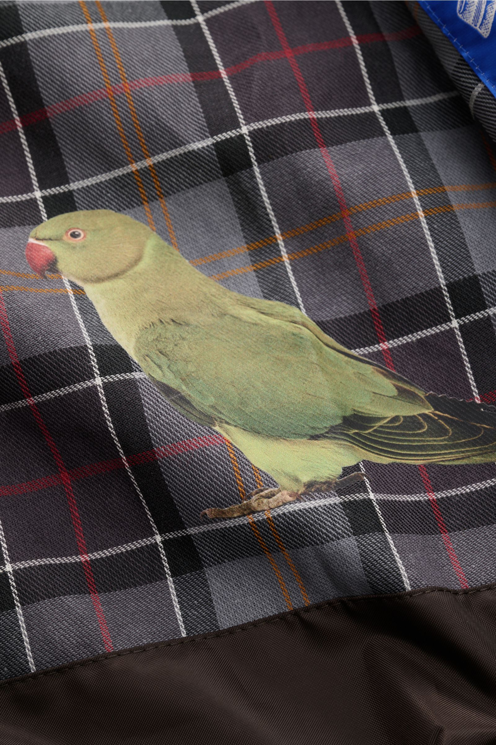 Nahaufnahme des typischen Tartan-Innenfutters mit Vogel-Print der Barbour Wachsjacke 'Transport' bordeaux aus gewachster Baumwolle.