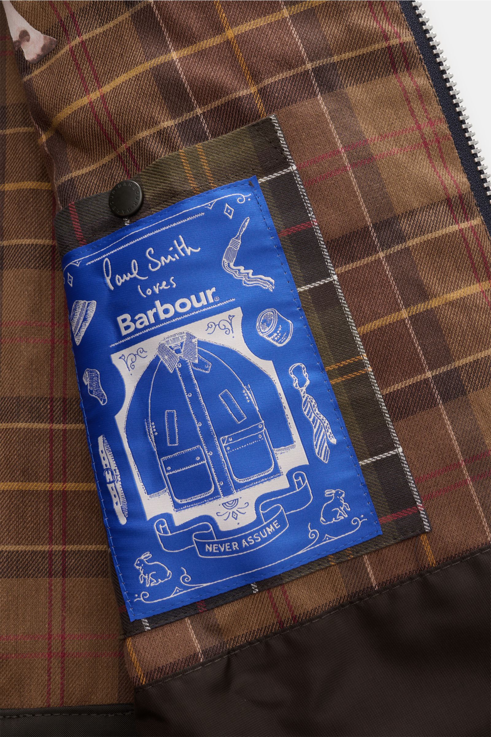 Nahaufnahme des braun karierten Innenfutters mit blauem Paul Smith Label der Barbour Wachsjacke 'Bedale' navy aus gewachster Baumwolle.