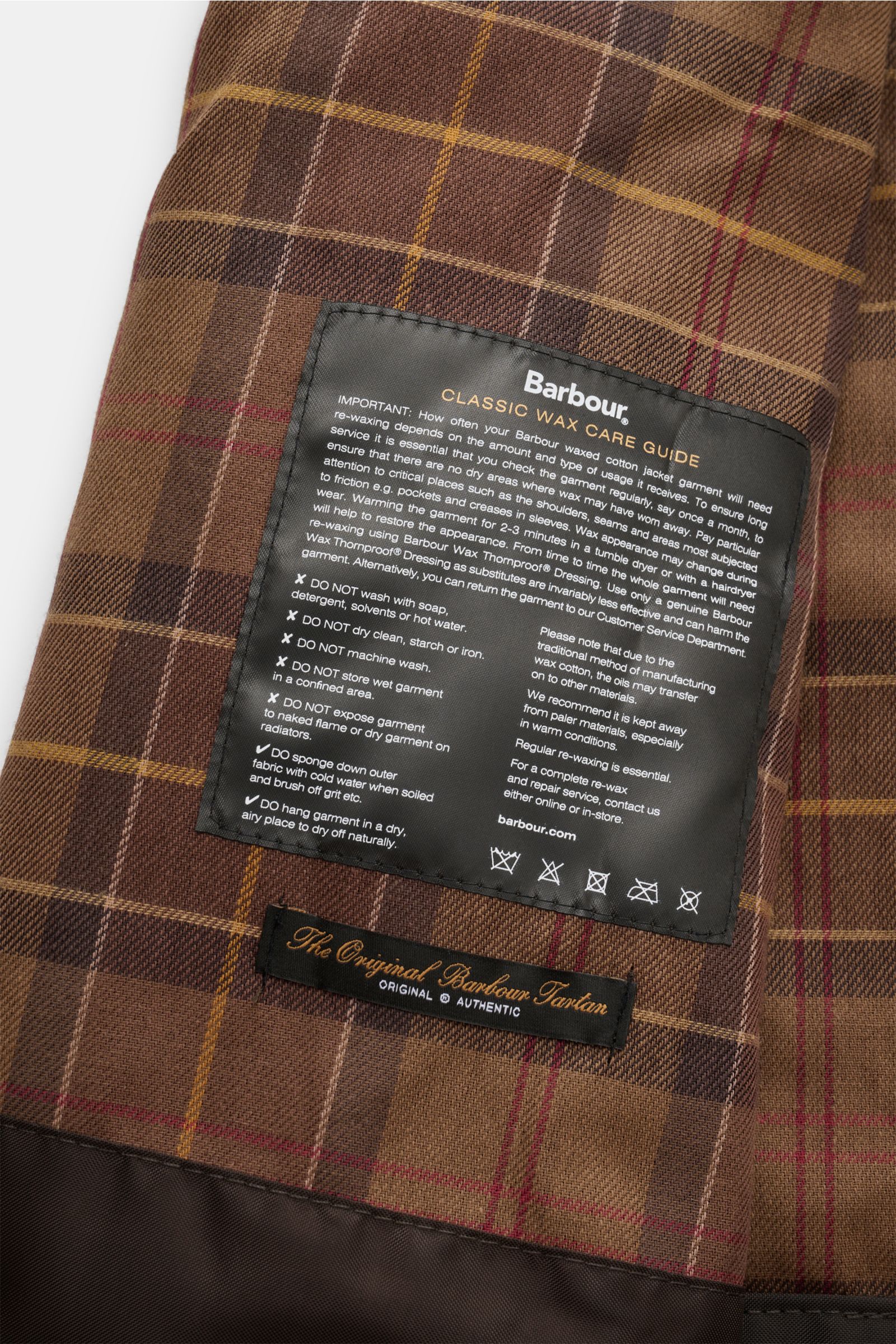 Innenansicht des Tartan-Innenfutters mit Kuh-Print und Pflegeetikett der Barbour Wachsjacke 'Bedale' navy aus gewachster Baumwolle.