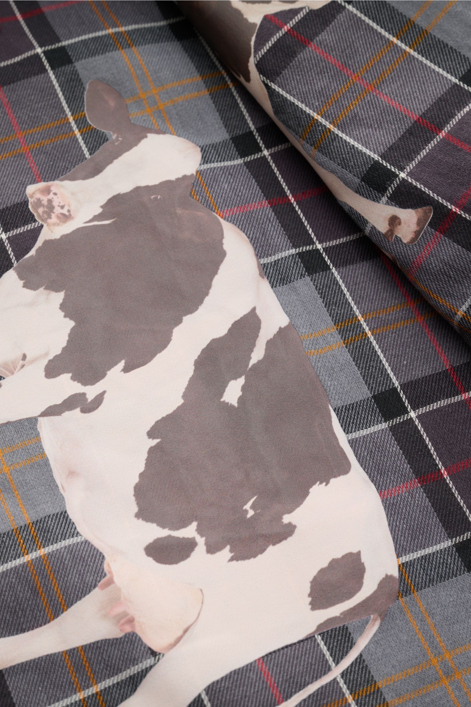 Nahaufnahme des Kuh-Prints auf dem Tartan-Innenfutter der Barbour Wachsjacke 'Bedale' braun aus gewachster Baumwolle.