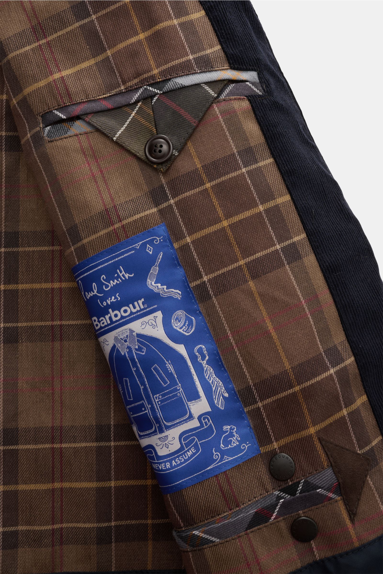 Close-up inside view of the Barbour Wachsparka 'Beeston' navy showing brown tartan lining, buttoned inner pocket flap, and blue Paul Smith x Barbour label. Gut gerüstet für die Übergangszeit: Der 'Beeston' Wachsparka gehört zur Kooperationskollektion von 