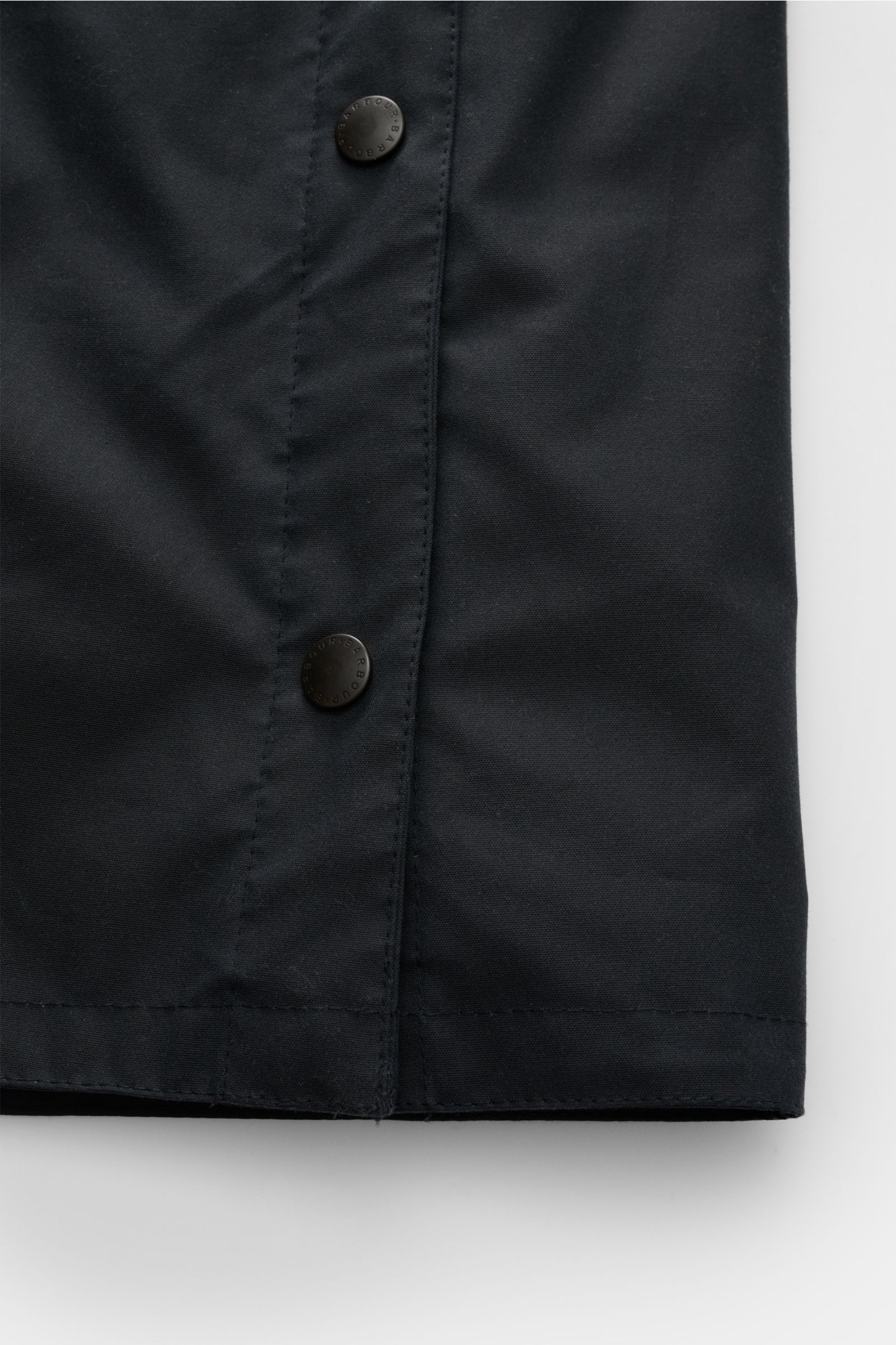 Close-up front detail of the Barbour Wachsparka 'Beeston' navy showing the waxed cotton fabric and snap buttons. 

Gut gerüstet für die Übergangszeit: Der 'Beeston' Wachsparka gehört zur Kooperationskollektion von BARBOUR und PAUL SMITH und besteht - wie 