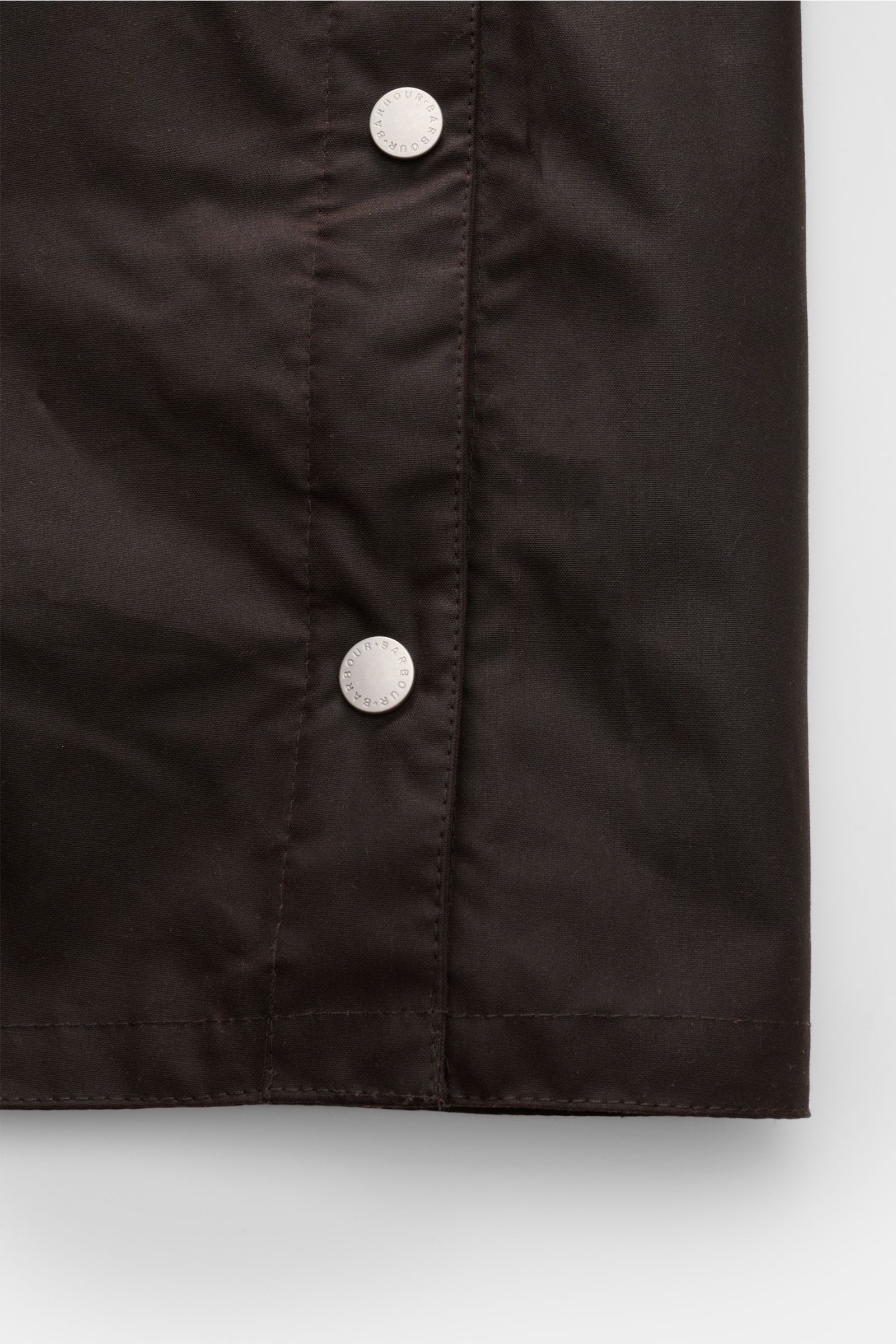 Nahaufnahme des Barbour Wachsparka 'Beeston' dunkelbraun mit gewachster Baumwolle, Druckknöpfen und materialtypischem Griff.