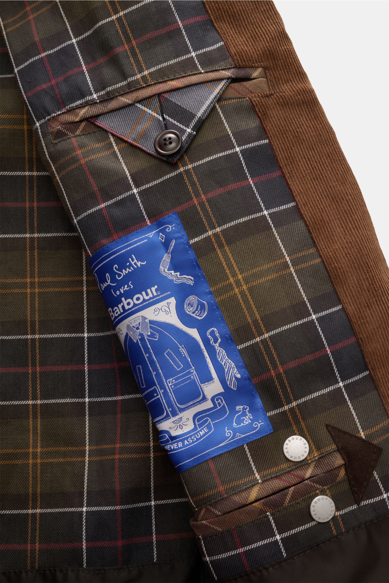 Detailaufnahme des Barbour Wachsparka 'Beeston' dunkelbraun Innenfutters mit Tartan-Muster, Cordbesatz und Paul Smith Label.