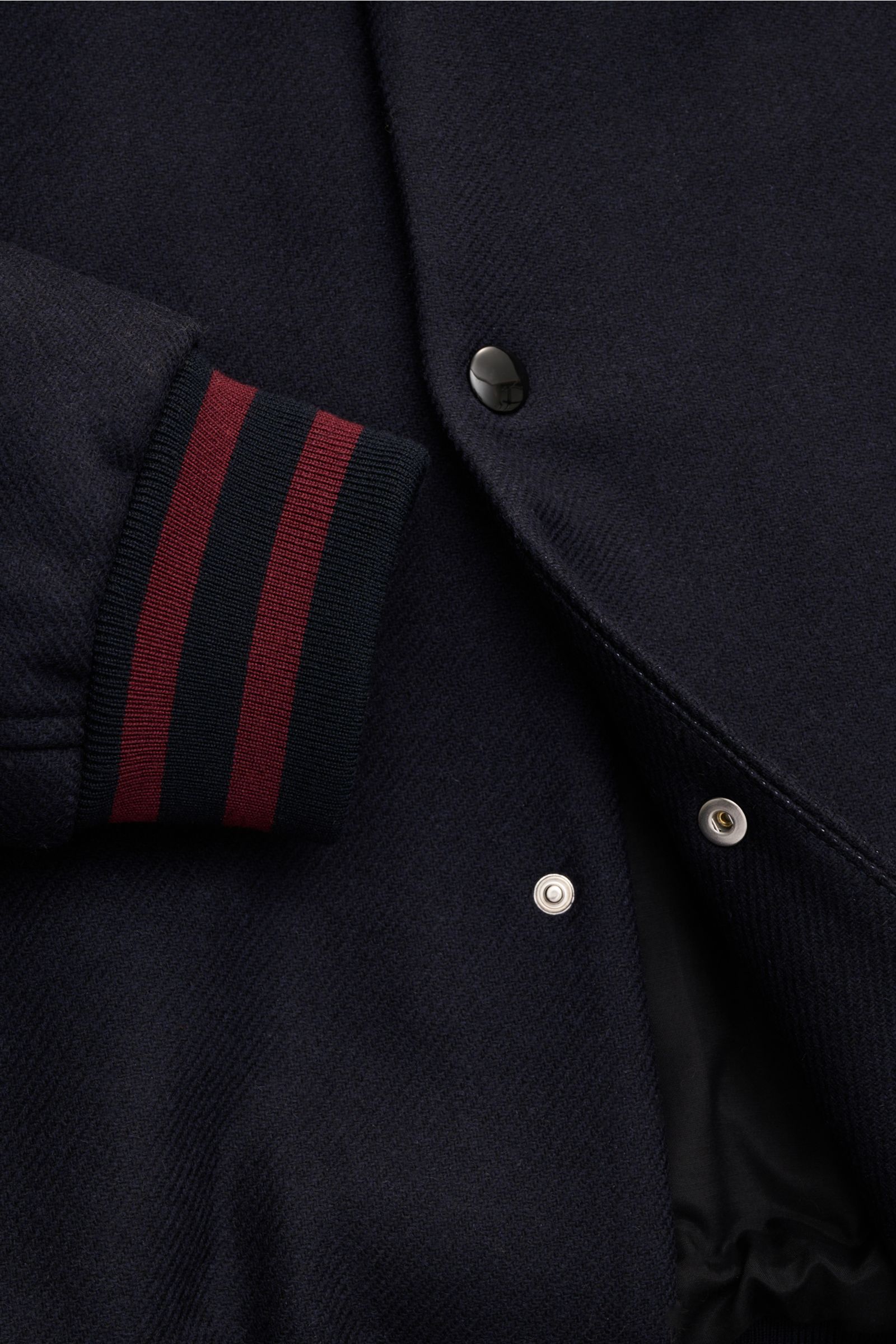 Ausschnitt des A.P.C. Blouson 'Micky' dark navy im College-Style, Woll-Mix, Rippbündchen mit roten Streifen, Druckknopfleiste, schräge Taschen.