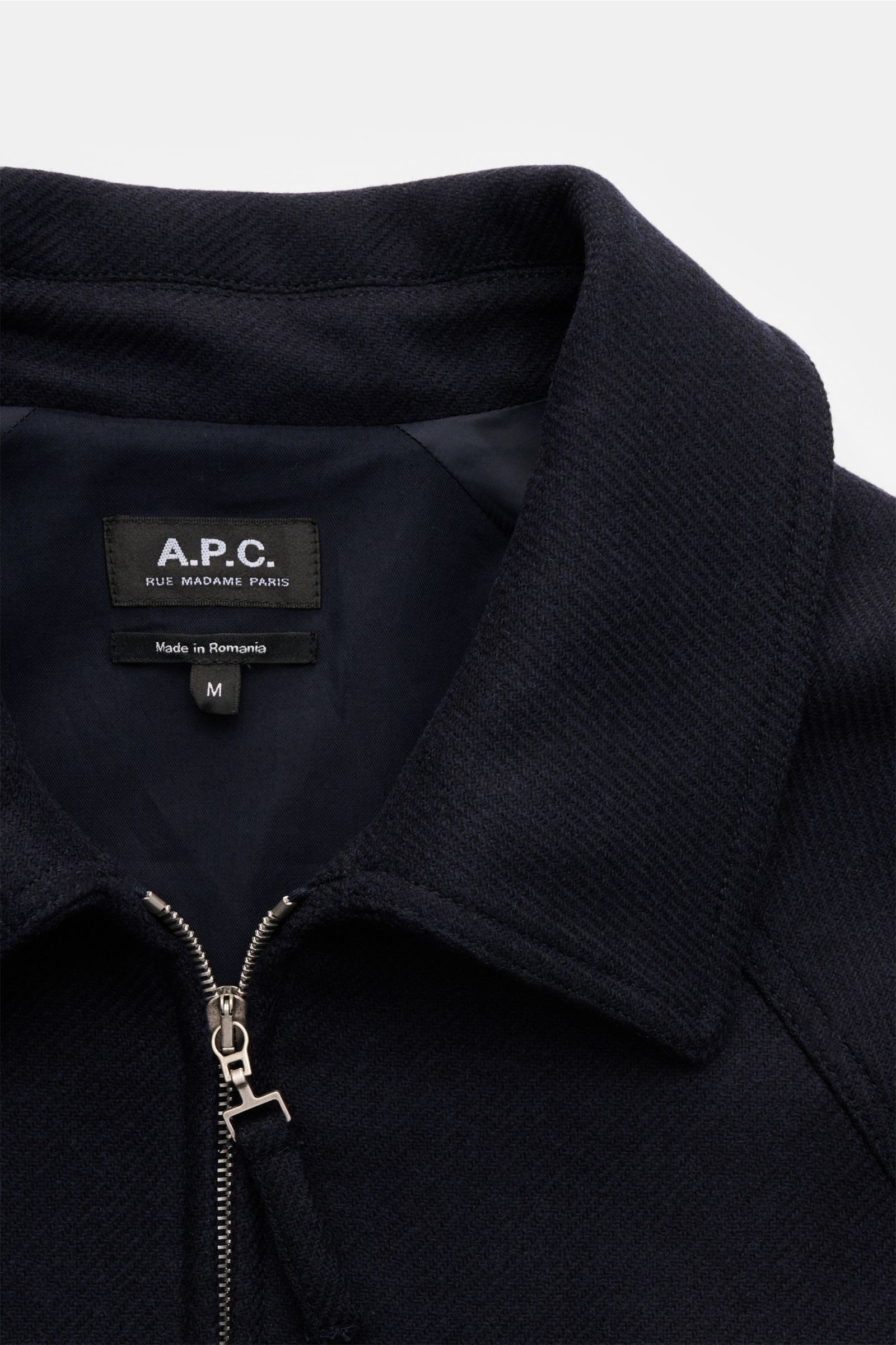 A close-up front view of the collar and zipper of the A.P.C. Jacke 'Chase' navy, made from a durable wool-microfiber mix with a regular fit, raglan sleeves, slanted welt pockets, and a viscose lining. Die Jacke 'Chase' vom Französischen Label A.P.C. fe