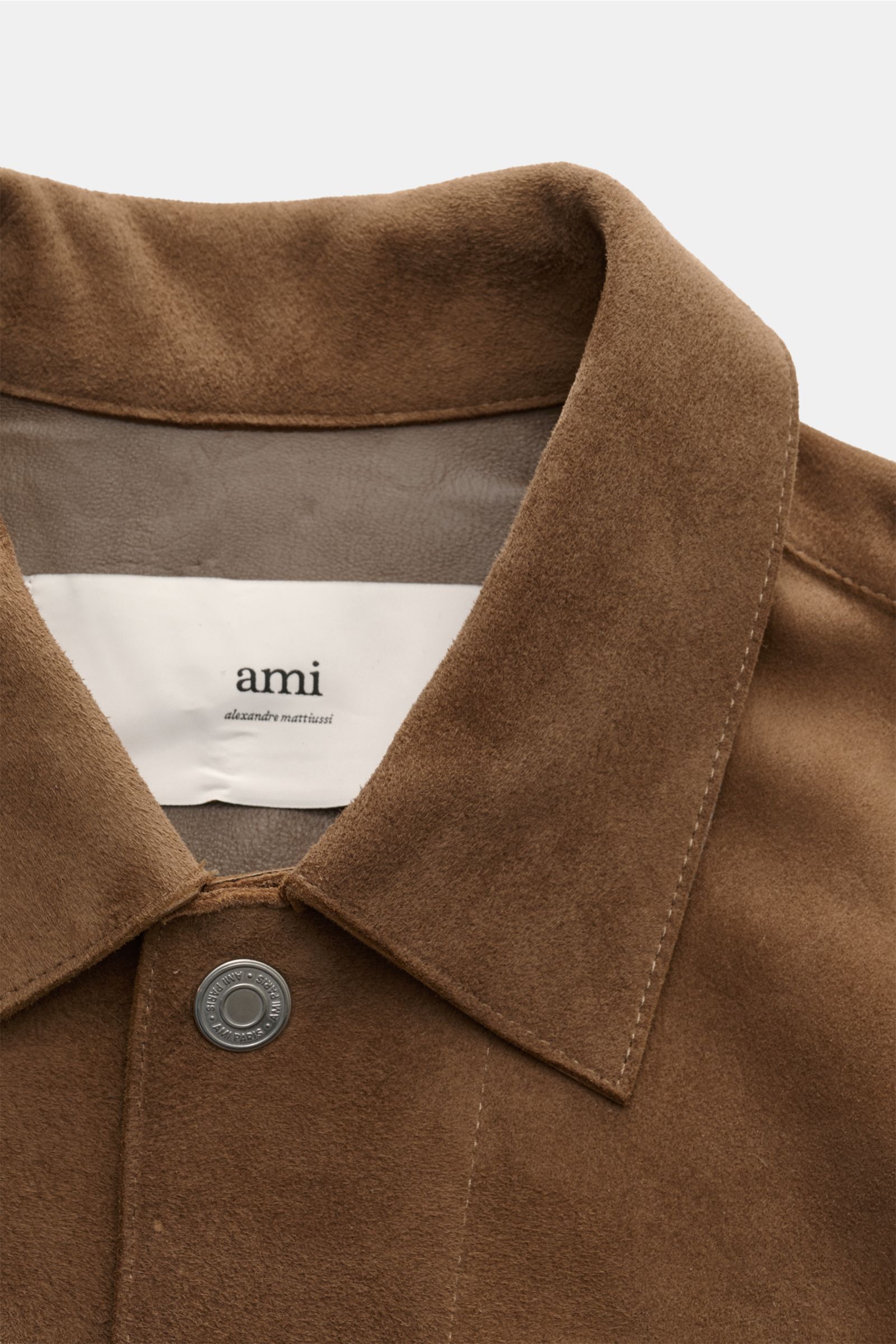 Nahaufnahme der Ami Paris Velourslederjacke hellbraun von oben, Regular Fit mit Umlegekragen, Druckknopfleiste, weichem Veloursleder und Logo-Patch.