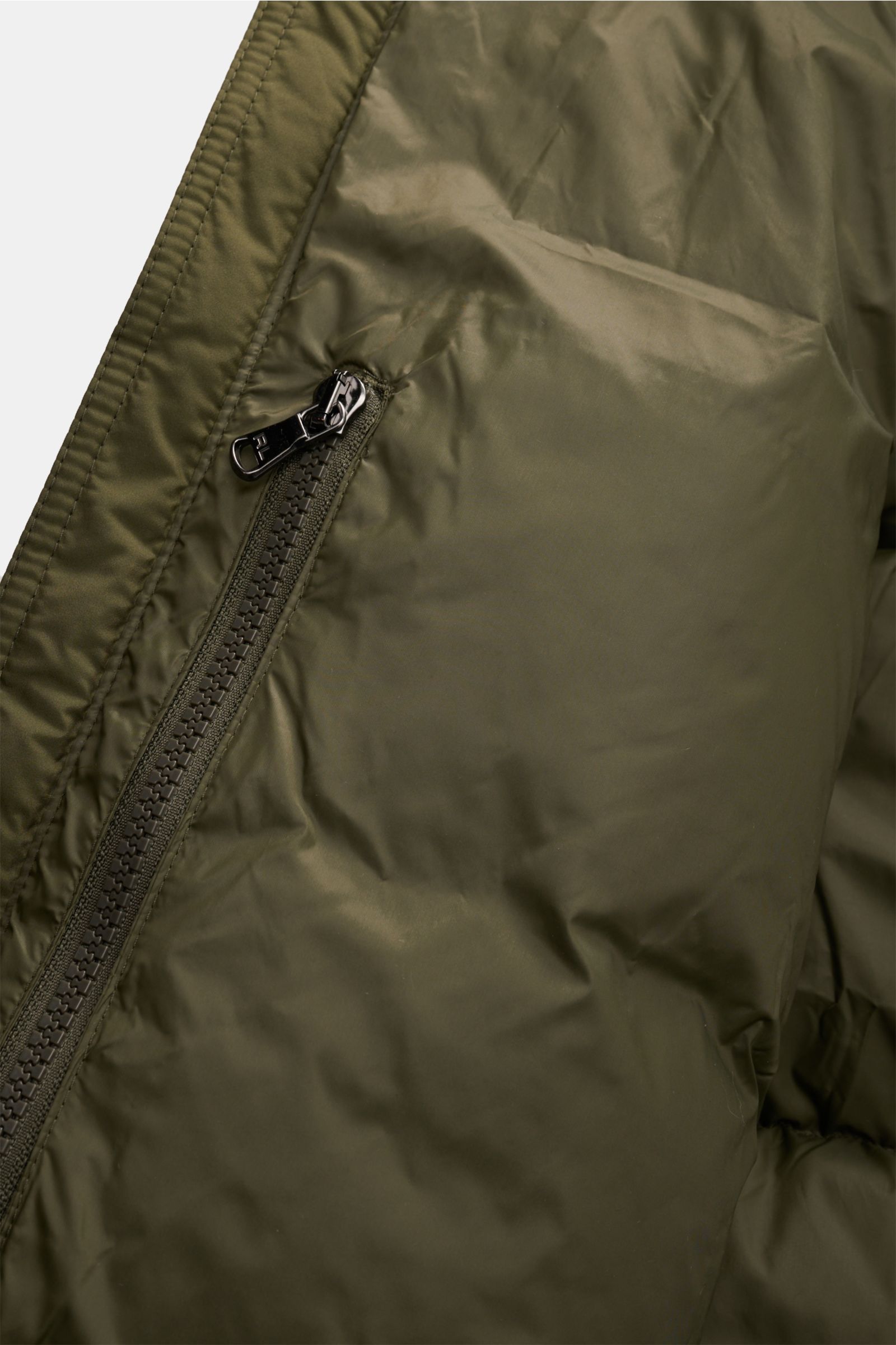 Close-up front view of the Polo Ralph Lauren Daunenjacke oliv showing the shiny olive fabric and a zipper pocket. Setzen Sie ein Statement - auch im Winter: Diese Daunenjacke von POLO RALPH LAUREN wärmt dank ihrer Daunenfüllung garantiert bei kalten Te