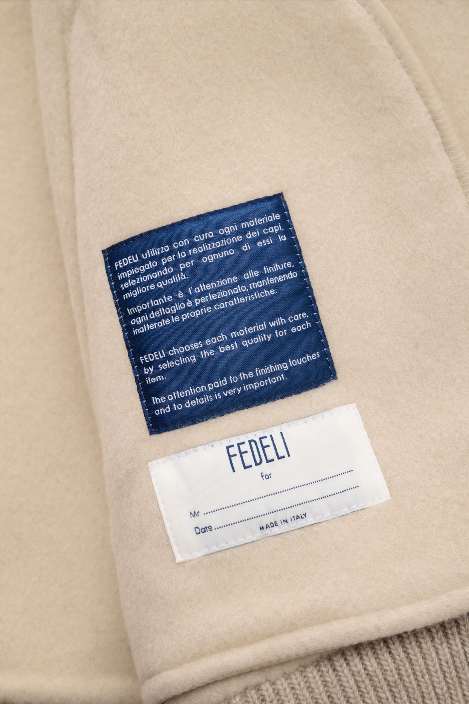 Fedeli Blouson 'Solferino' beige Detailaufnahme Innenfutter mit blauen und weißen Markenlabels aus Schurwolle und Cashmere, weicher Griff.