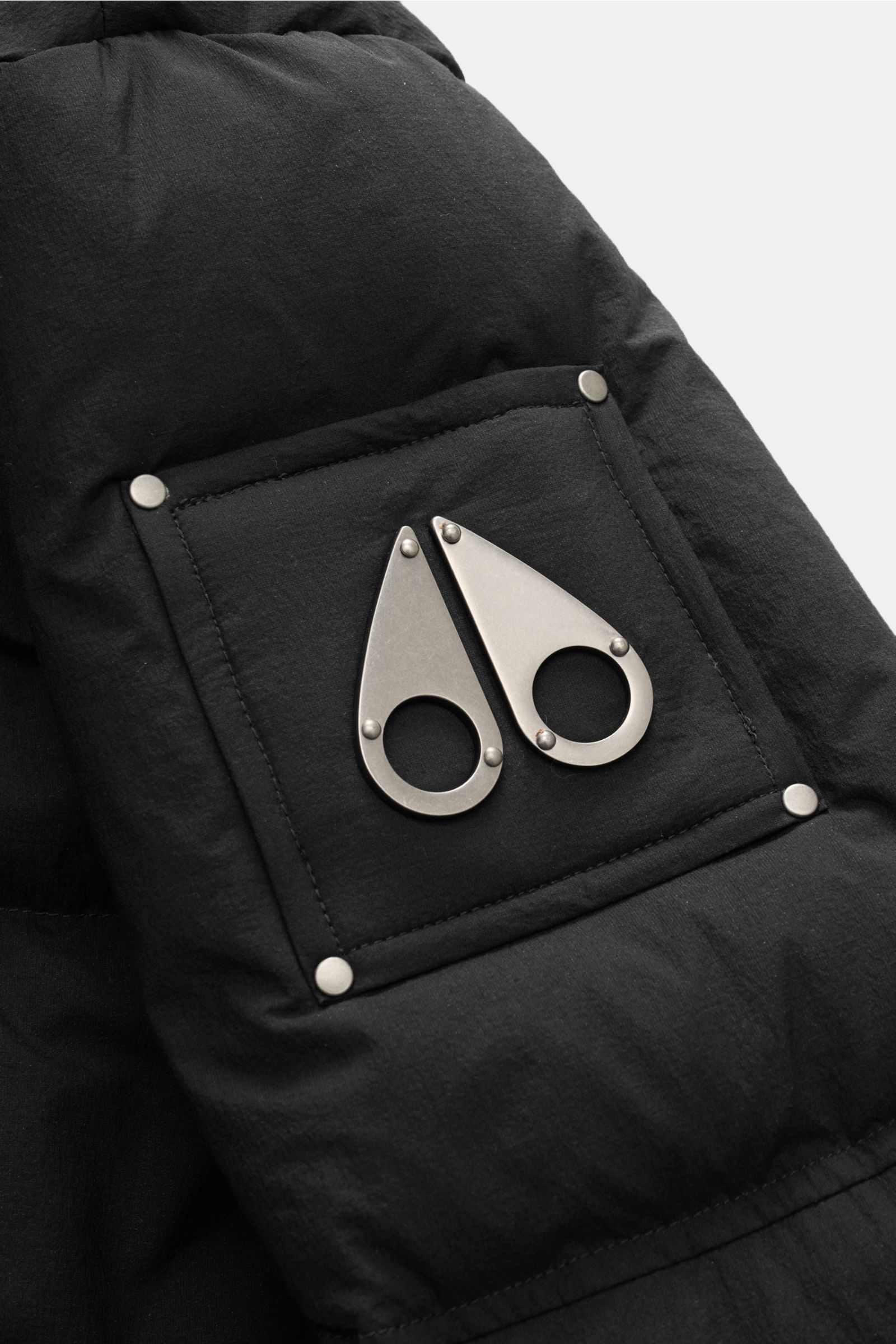 Moose Knuckles Daunenmantel 'Everest Long Puffer' schwarz, Detailaufnahme Logo am Oberarm, Microfaser, wind- und wasserabweisend, Daunenfüllung.