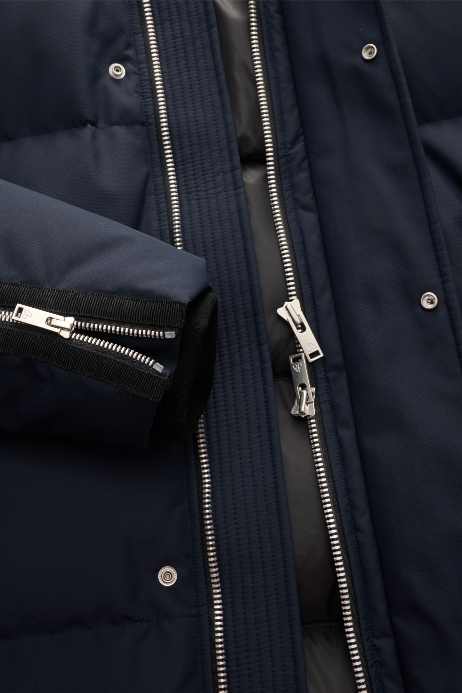 Nahaufnahme der geöffneten Moose Knuckles Daunenjacke 'Cloud 3Q' navy, zeigt den Zwei-Wege-Reißverschluss, wind- und wasserabweisende Microfaser, komfortable Rippbündchen am Ärmel und hochwertige Daunenfüllung, fotografiert aus Frontalperspektive.