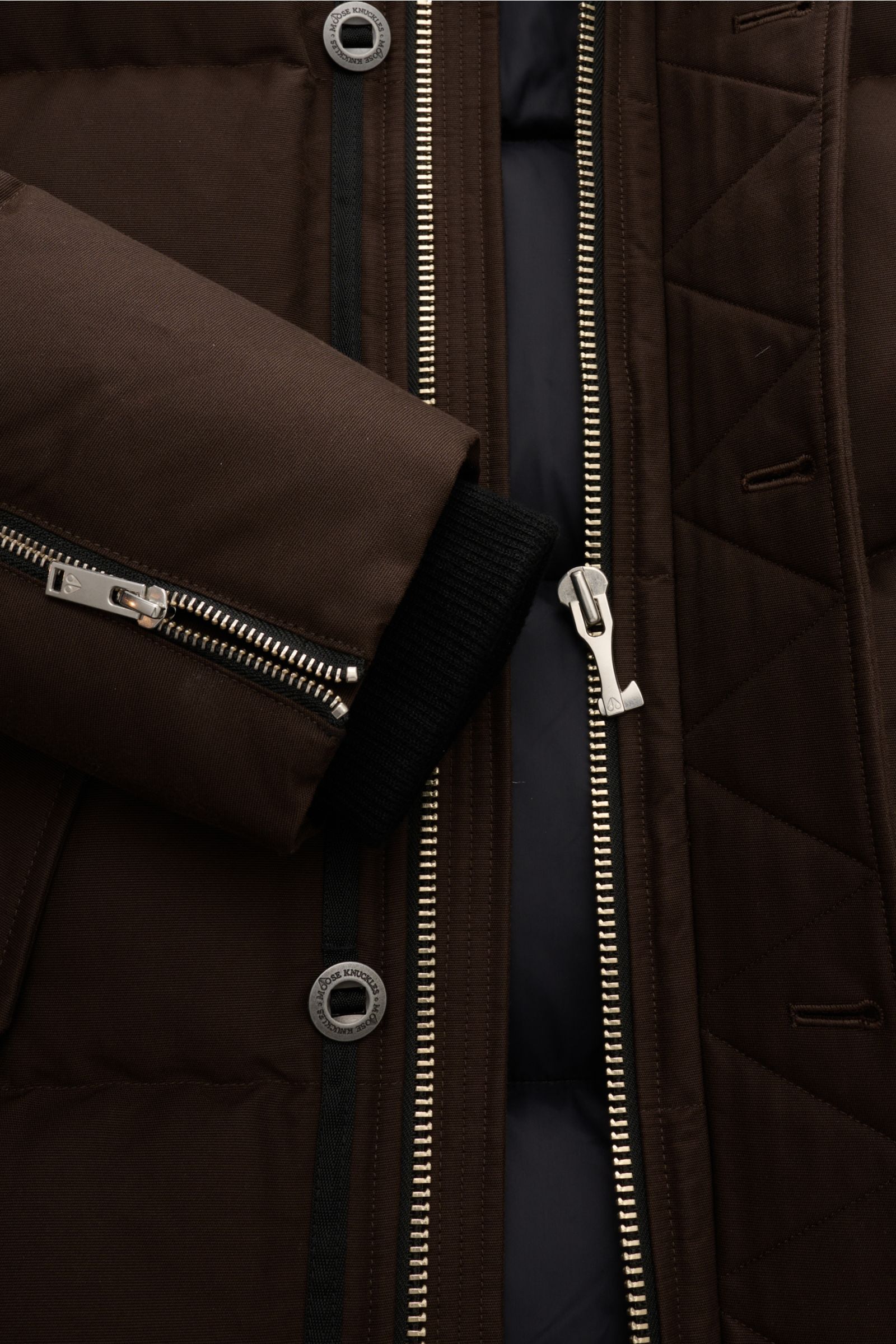 Close-up front view of the Moose Knuckles Down jacket 'Original 3q Neoshear' dark brown, showing zippers, button, and ribbed cuff. Effortlessly protects against even extreme cold: With its high-quality 90/10 down lining, this MOOSE KNUCKLES jacket deliver