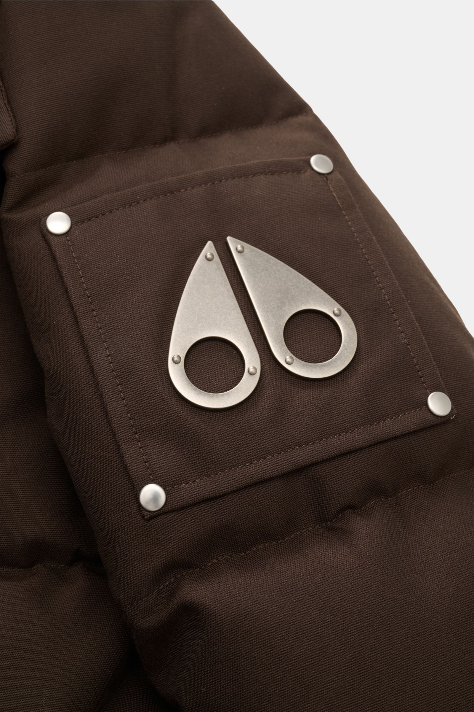 Close-up angled view of the dark brown Moose Knuckles Down jacket 'Original 3q Neoshear' sleeve pocket with metal logo, cotton-microfibre blend, wind and water repellent, warm down lining, slim fit, detachable hood and fur trim, storm flap, multiple pocke