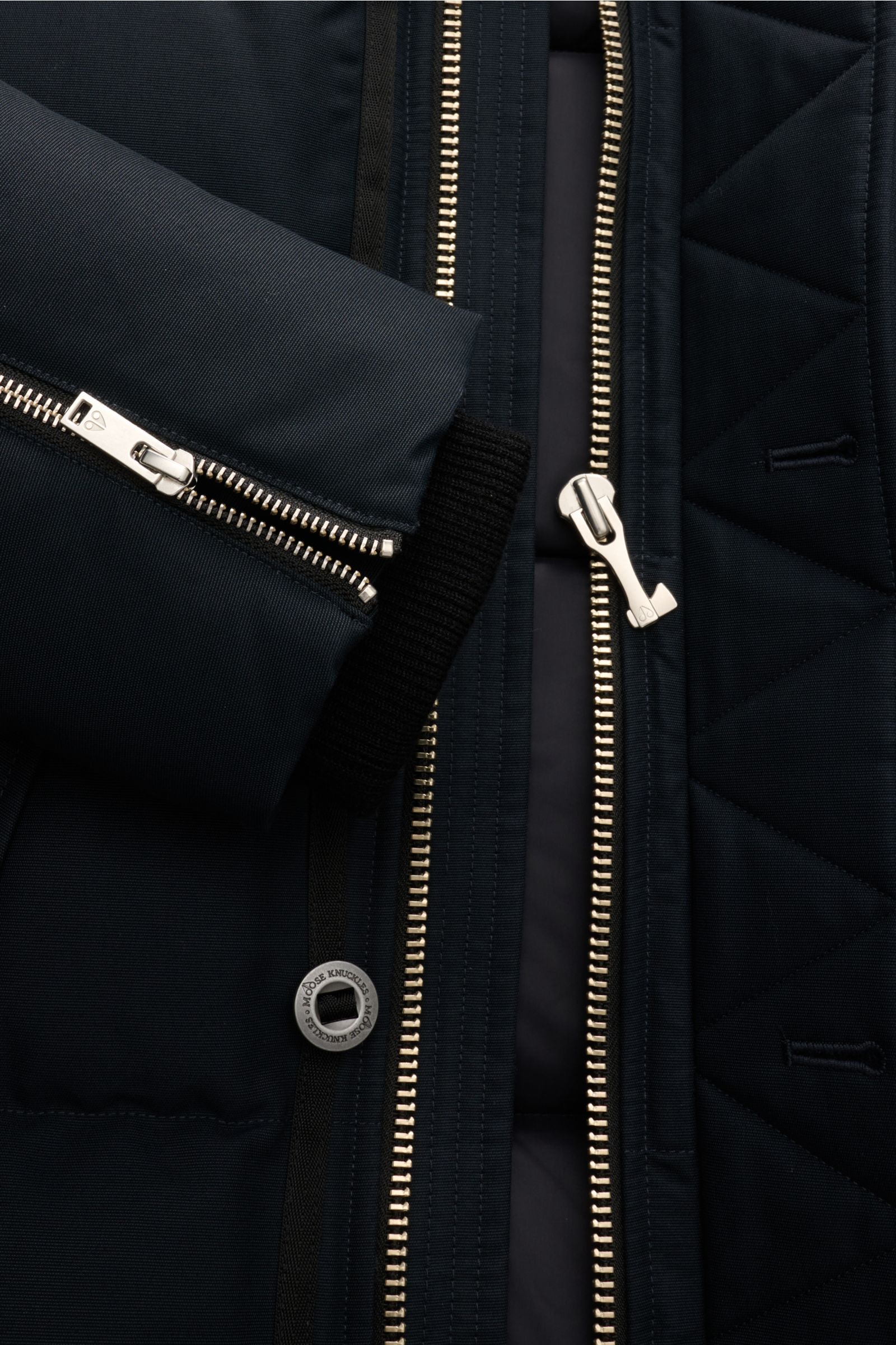 Close-up front view of the Moose Knuckles Down jacket 'Original 3q Neoshear' navy, showing silver zippers, a button with logo, and quilted fabric. Effortlessly protects against even extreme cold: With its high-quality 90/10 down lining, this MOOSE KNUCKLE