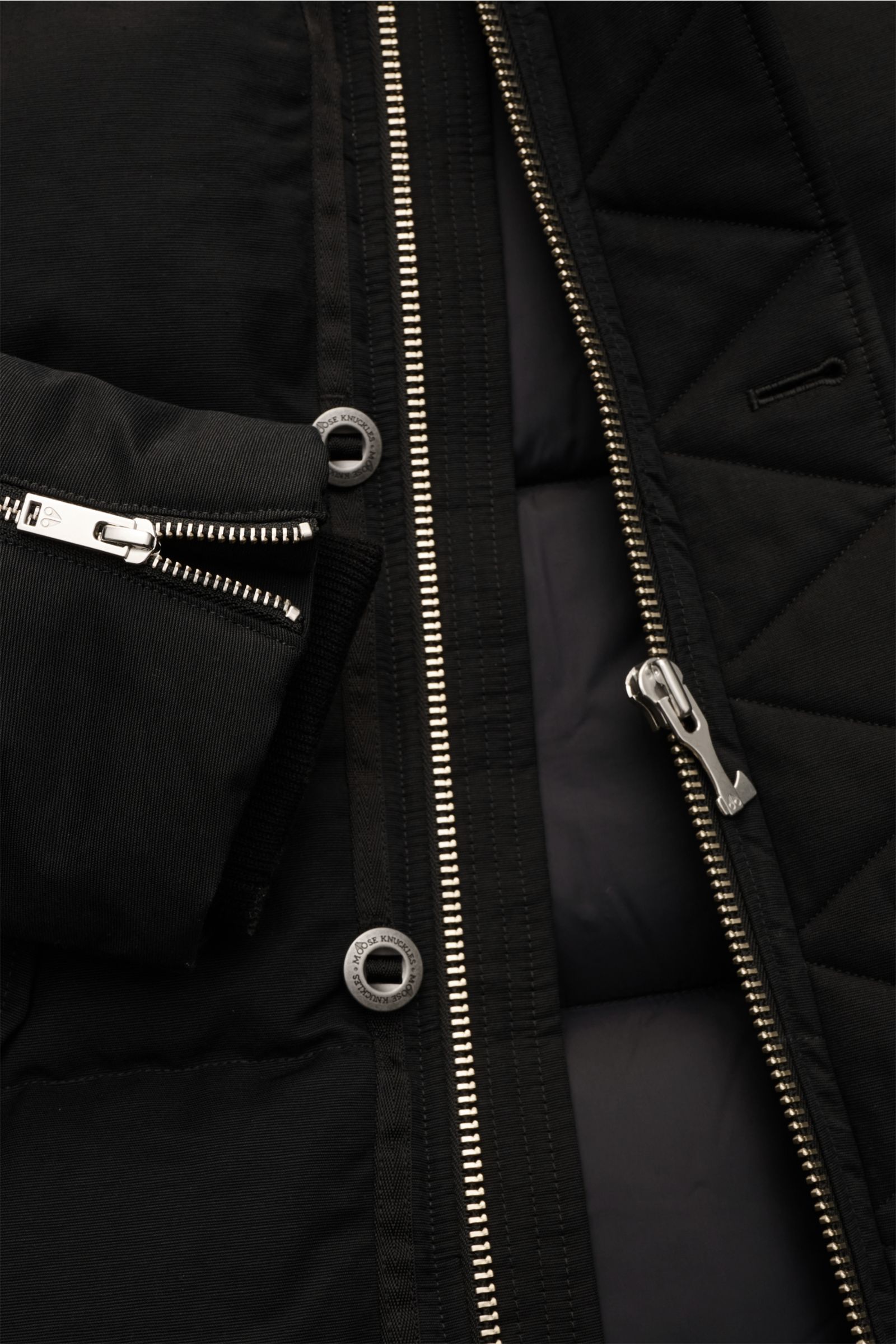 Close-up front view of the Moose Knuckles Daunenjacke 'Original 3q Neoshear' schwarz showing the black jacket’s silver zipper, snap buttons, and detailed stitching, highlighting its wind- and water-repellent cotton-microfiber blend and warm 90/10 down fil