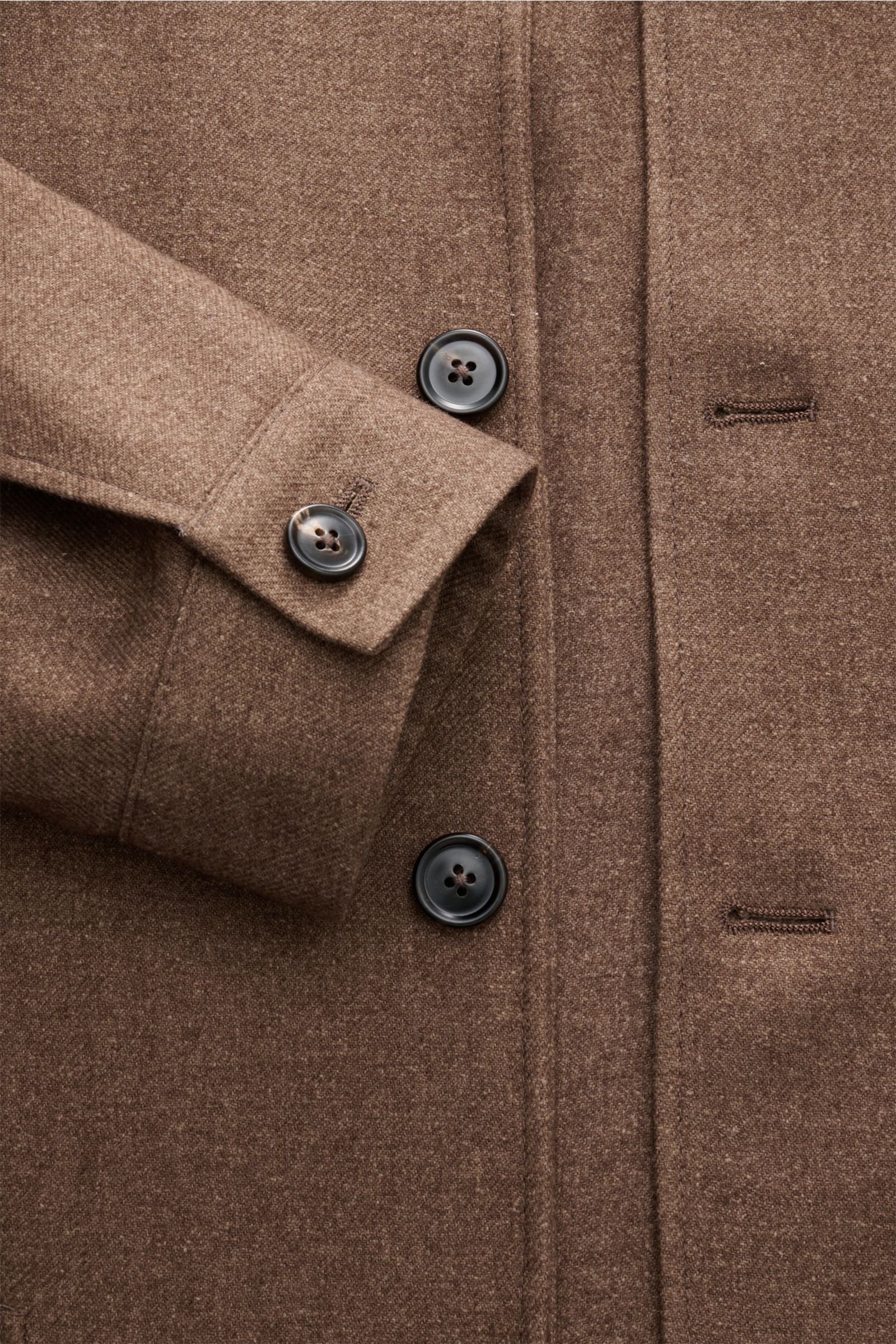 Nahaufnahme aus leicht schräger Perspektive einer braun melierten Zegna Jacke mit weichem Griff, Slim Fit, fünf-Knopf-Leiste, variabelm Stehkragen, Manschetten und rückwärtigem Leder-Detail, gefertigt aus Wolle, Seide und Leinen.